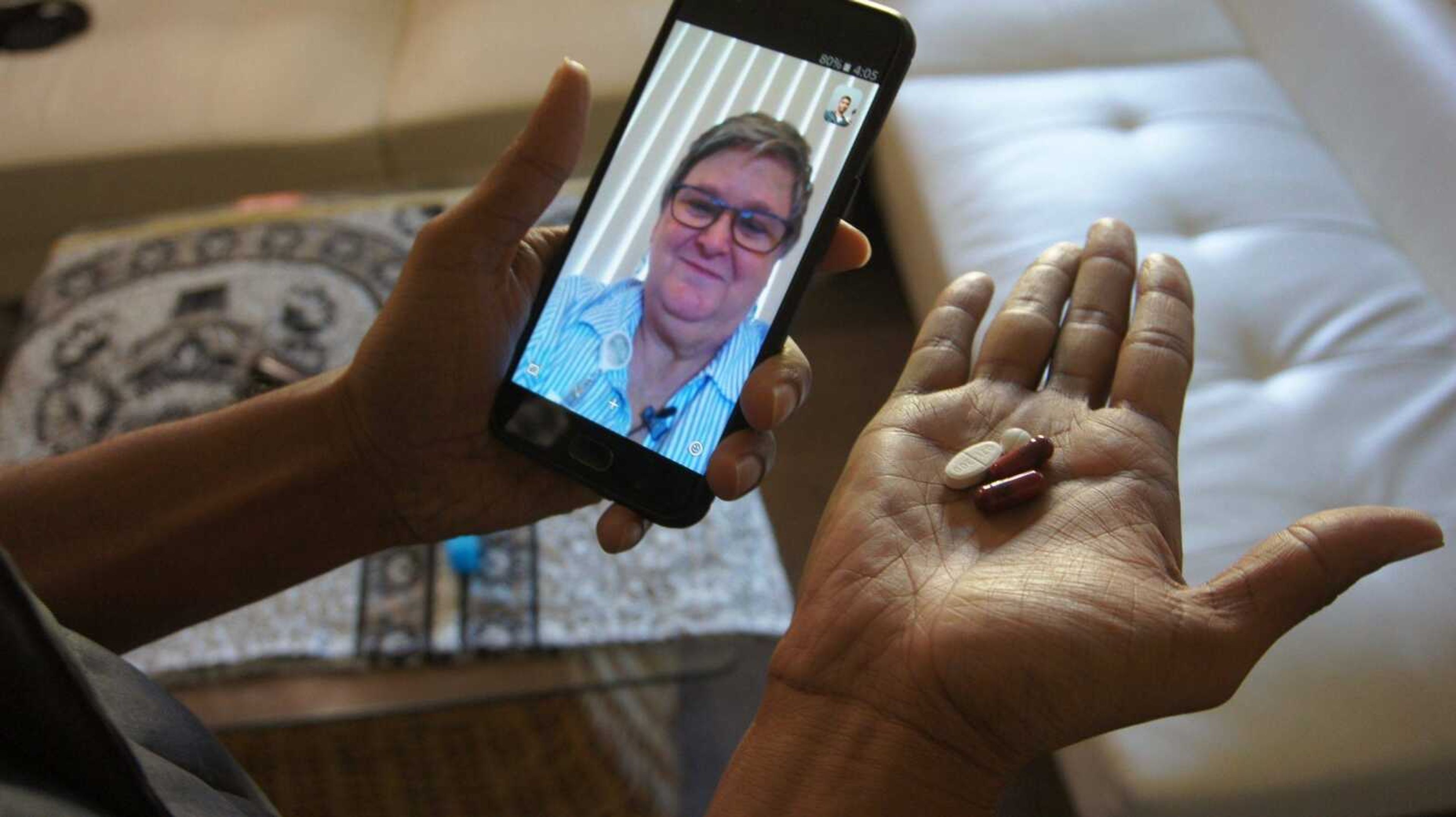 Public health nurse Peggy Cooley of the Tacoma-Pierce County Health Department, seen on the phone screen, uses Skype video to remotely monitor a patient taking antibiotics for tuberculosis at home in this March 15 photo in Lakewood, Washington.