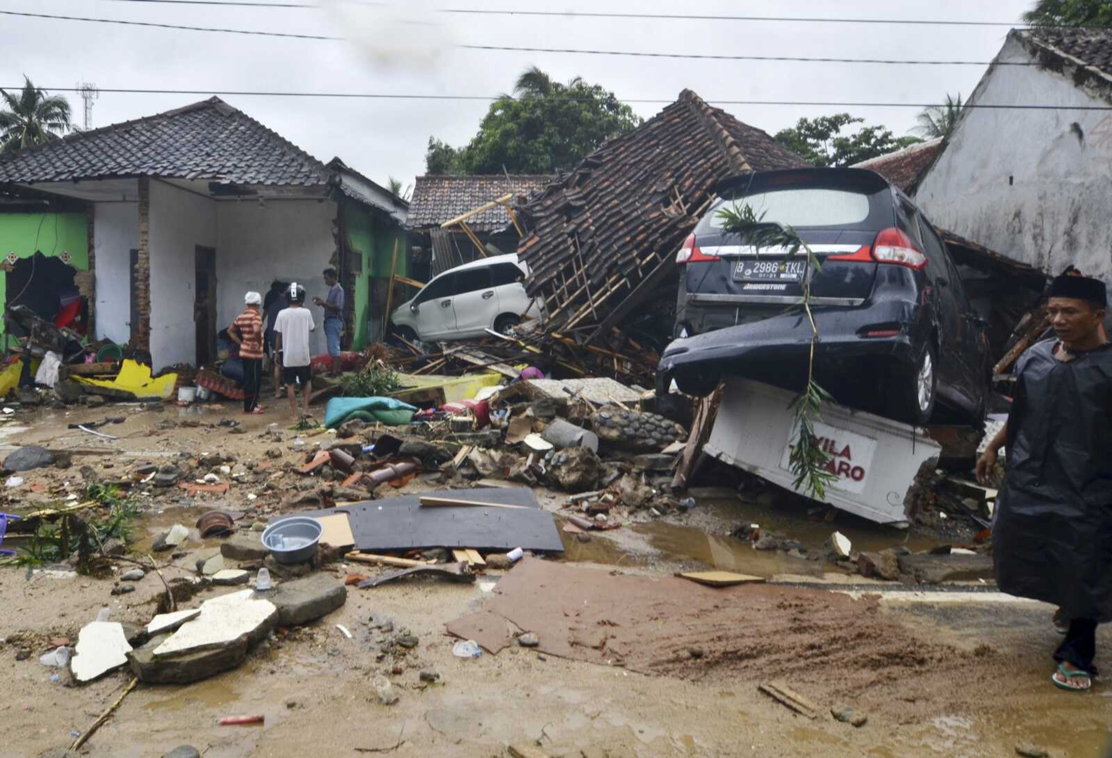 People inspect the damage at a tsunami-ravaged neighborhood Sunday in Carita, Indonesia.