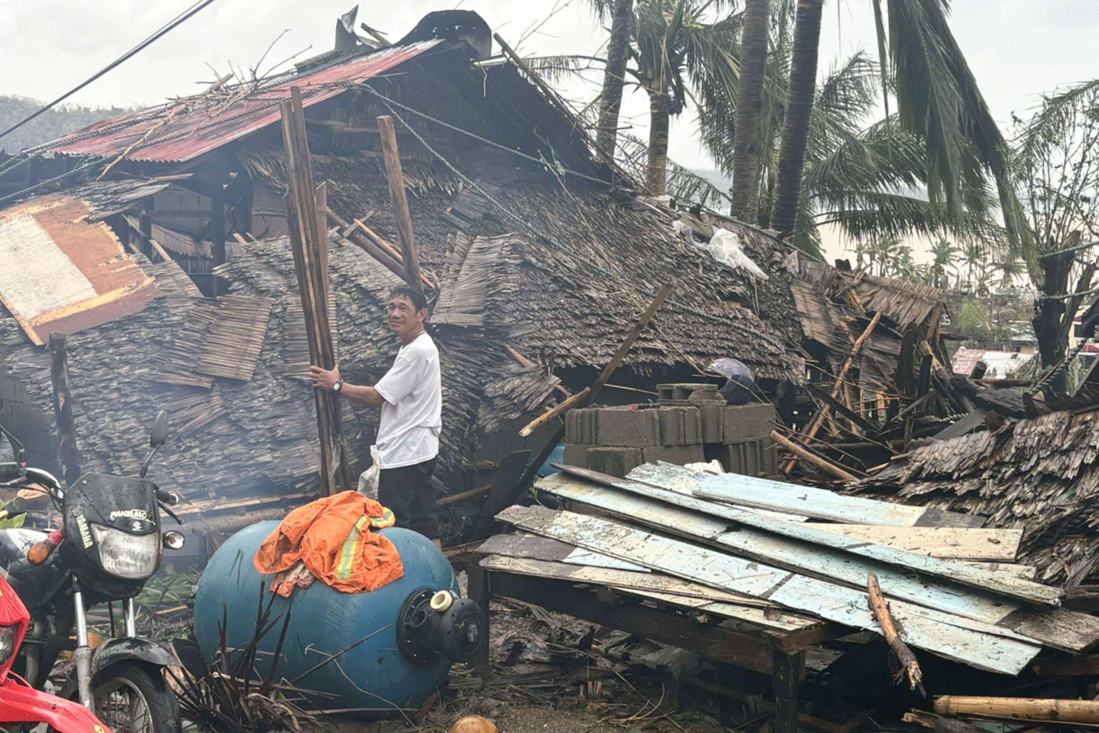 In this photo provided by the MDRRMO Viga Catanduanes, a resident stands beside a damaged house caused by Typhoon Man-yi in Viga, Catanduanes province, northeastern Philippines Sunday, Nov. 17, 2024. (MDRRMO Viga Catanduanes via AP)