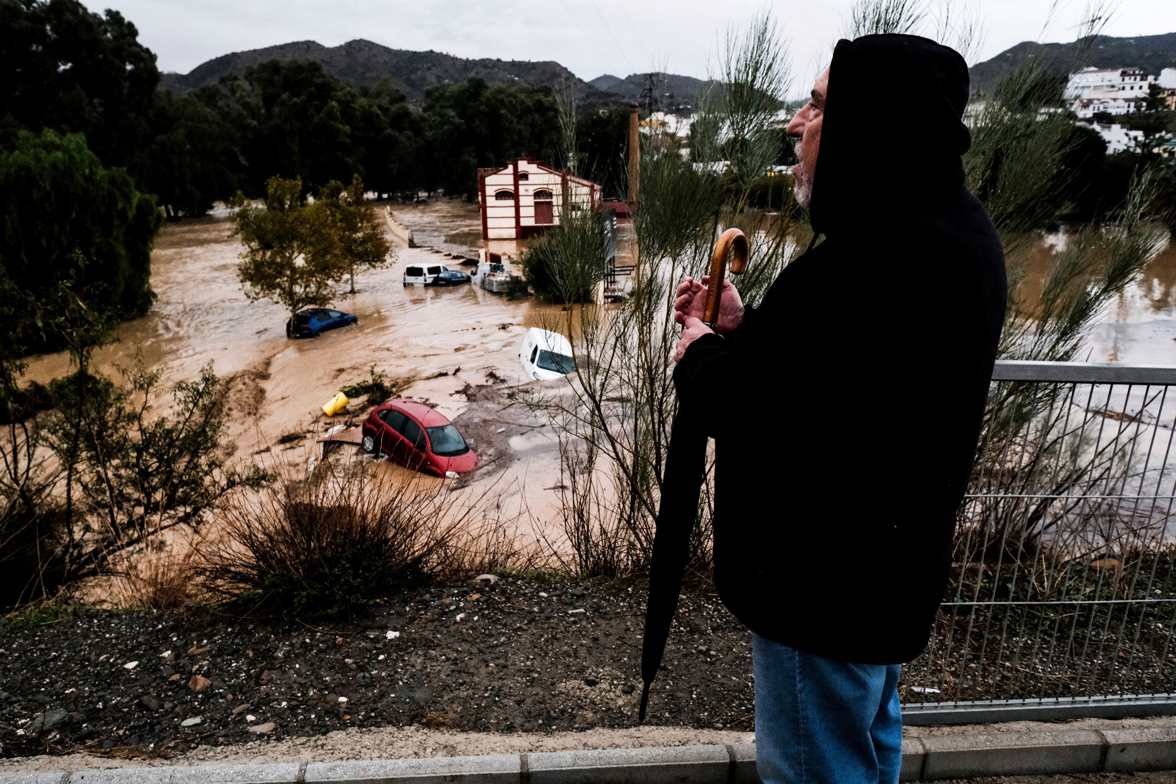 A man observes several cars being swept away by the water, after floods preceded by heavy rains caused the river to overflow its banks in the town of Alora, Malaga, Spain, Tuesday, Oct. 29, 2024. (AP Photo/Gregorio Marrero)