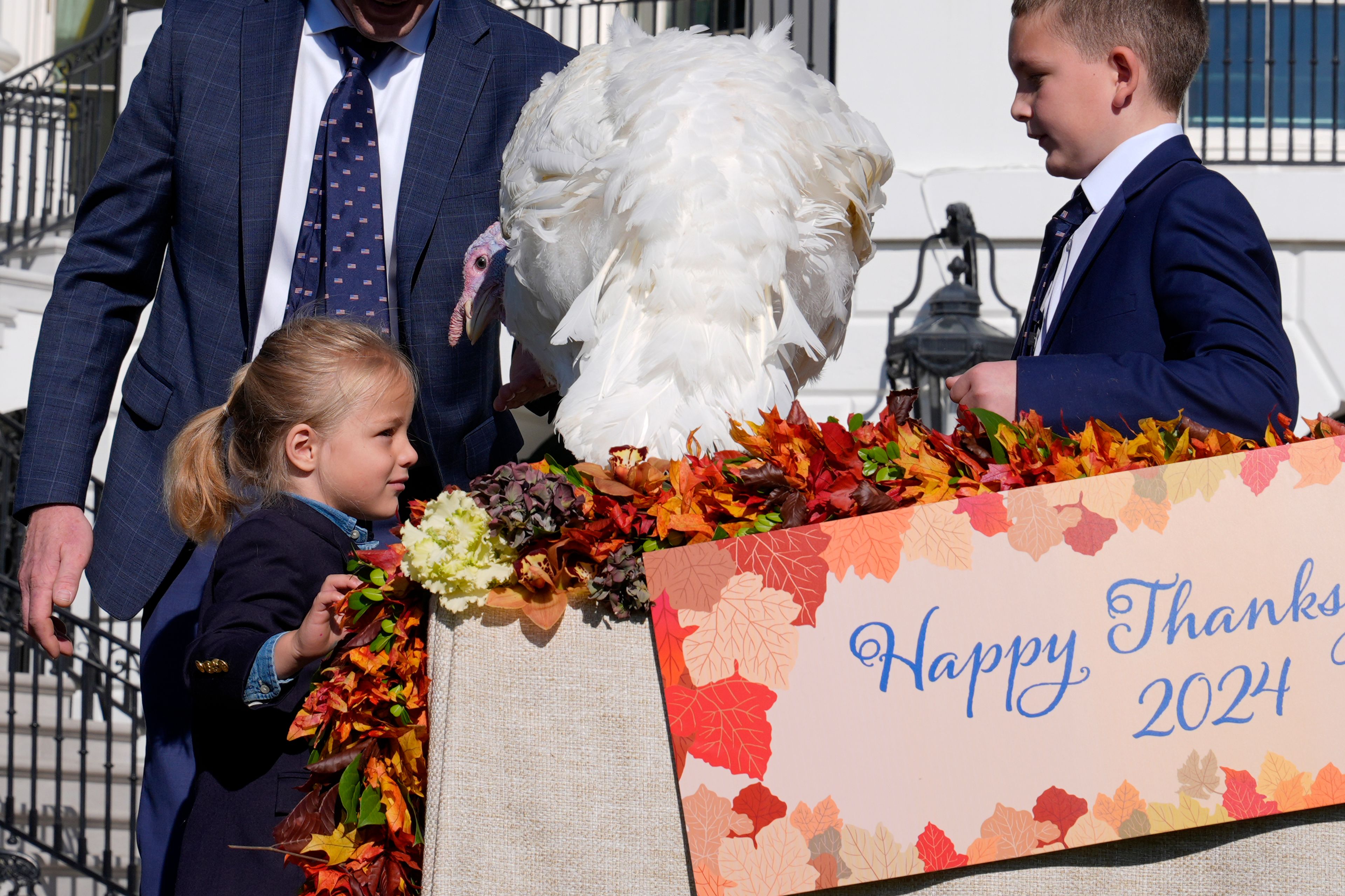 Beau Biden, left, looks at Peach, the national Thanksgiving turkey who was pardoned by President Joe Biden, during a ceremony on the South Lawn of the White House in Washington, Monday, Nov. 25, 2024. Grant Zimmerman, son of John Zimmerman, chair of the National Turkey Federation, watches at right. (AP Photo/Susan Walsh)