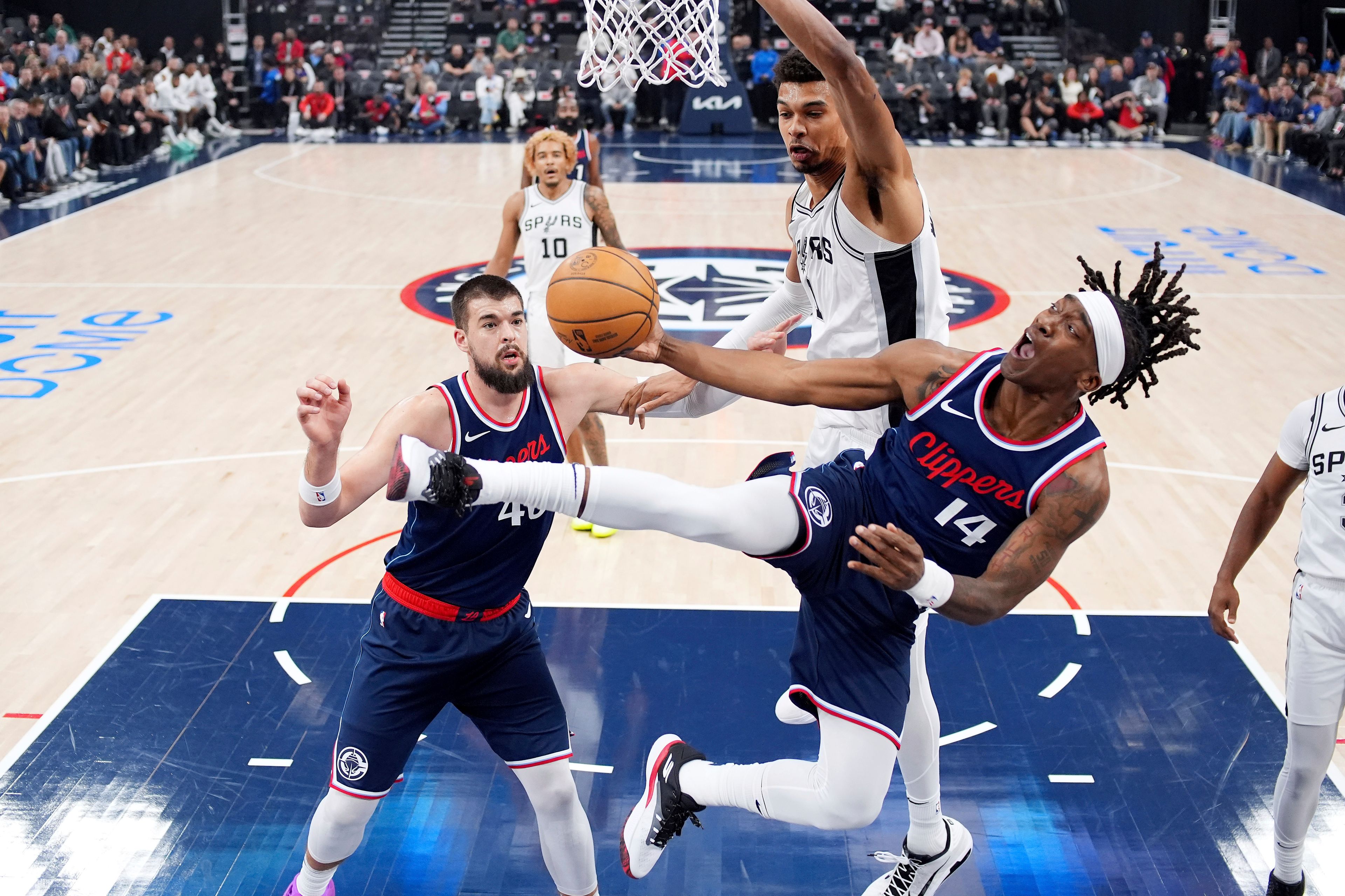 Los Angeles Clippers guard Terance Mann, right, shoots as San Antonio Spurs center Victor Wembanyama, top, defends and center Ivica Zubac watches during the first half of an NBA basketball game, Monday, Nov. 4, 2024, in Inglewood, Calif. (AP Photo/Mark J. Terrill)