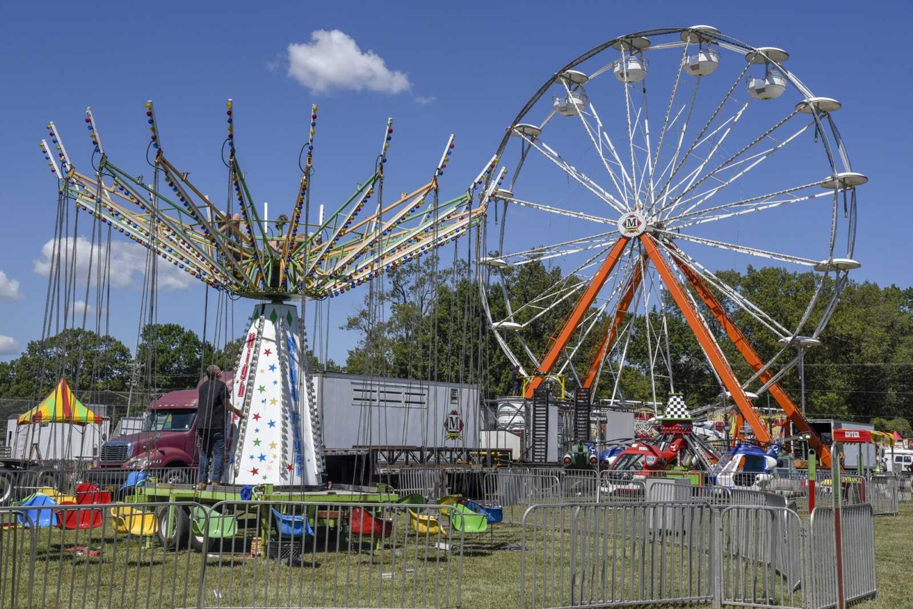 A crew sets up a swing ride while another crew attaches passenger cars to the ferris wheel ride Thursday before the 2021 SEMO District Fair begins at Arena Park in Cape Girardeau. The SEMO District Fair is returning Saturday after a year hiatus because of the pandemic. It will offer food, live entertainment, agricultural exhibits, amusement rides and more.