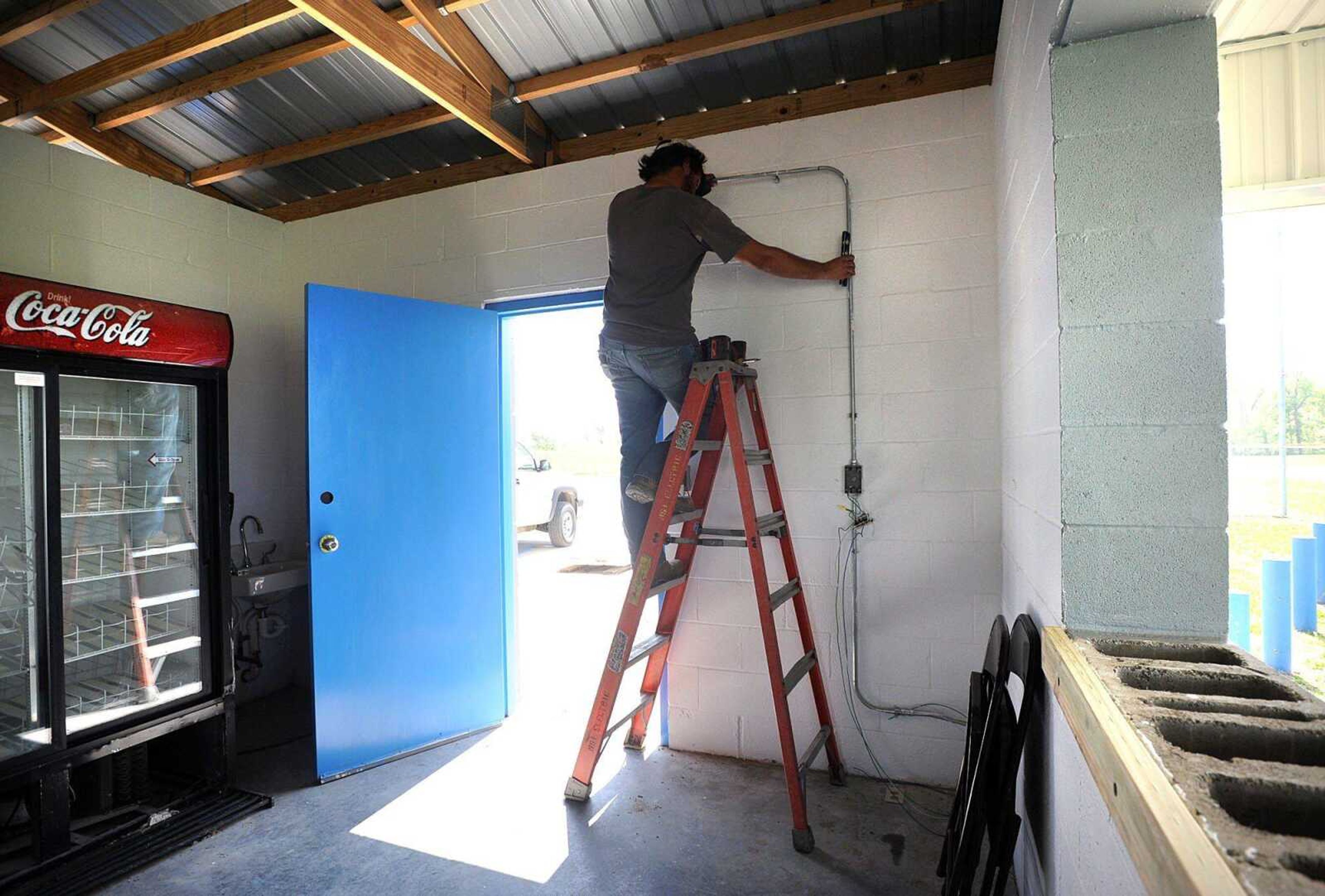 Cory Seabaugh with MSI Electric Inc. works on rewiring the concession stand Wednesday at Oak Ridge School. A tornado tore Feb. 29, caused extensive damage to the school. (Laura Simon)