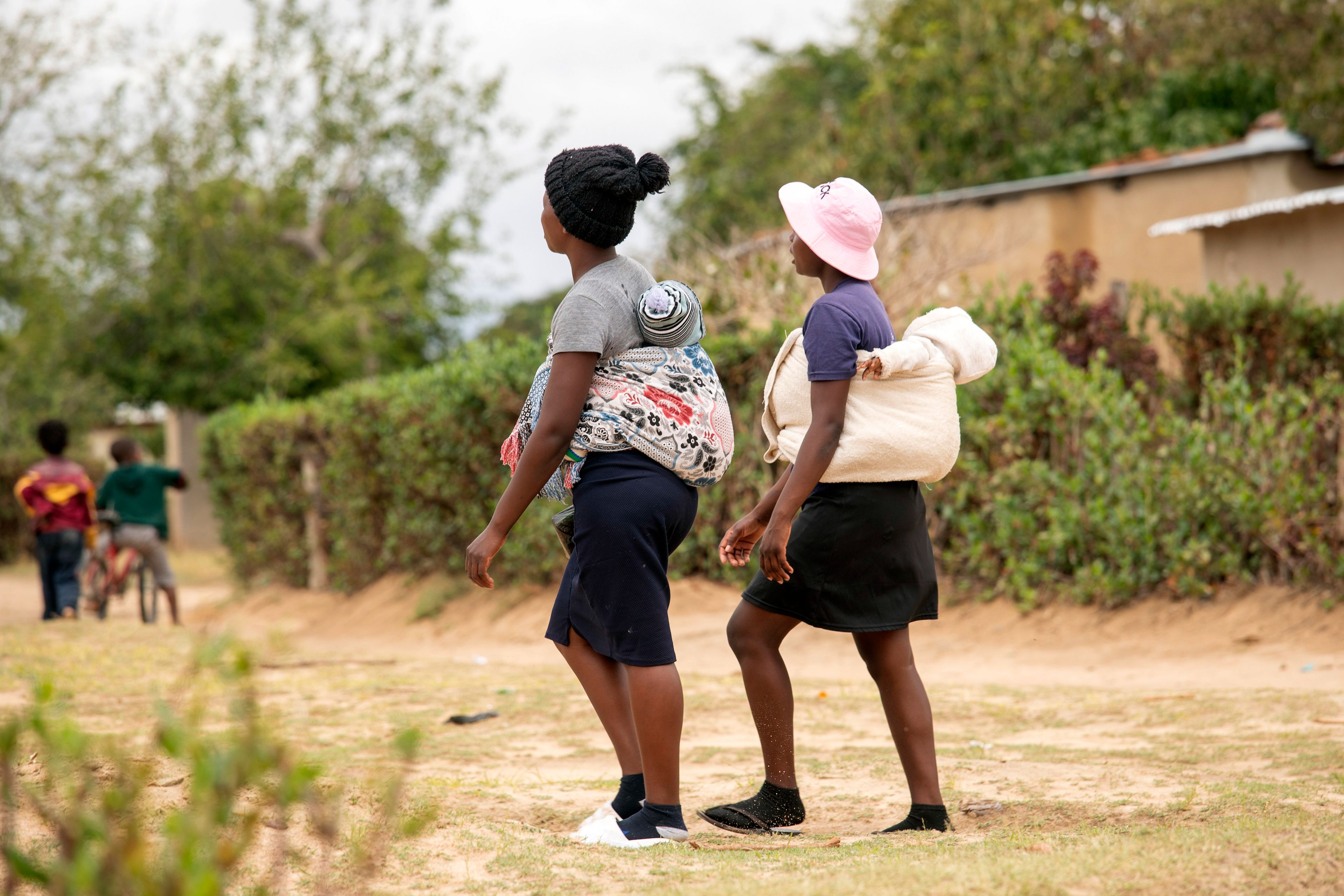 19 year old Sithulisiwe Moyo, right, and a friend, carry their babies on their backs at an outtreach clinic in Epworth, Zimbabwe, Thursday, Nov. 14, 2024. (AP Photo/Aaron Ufumeli)