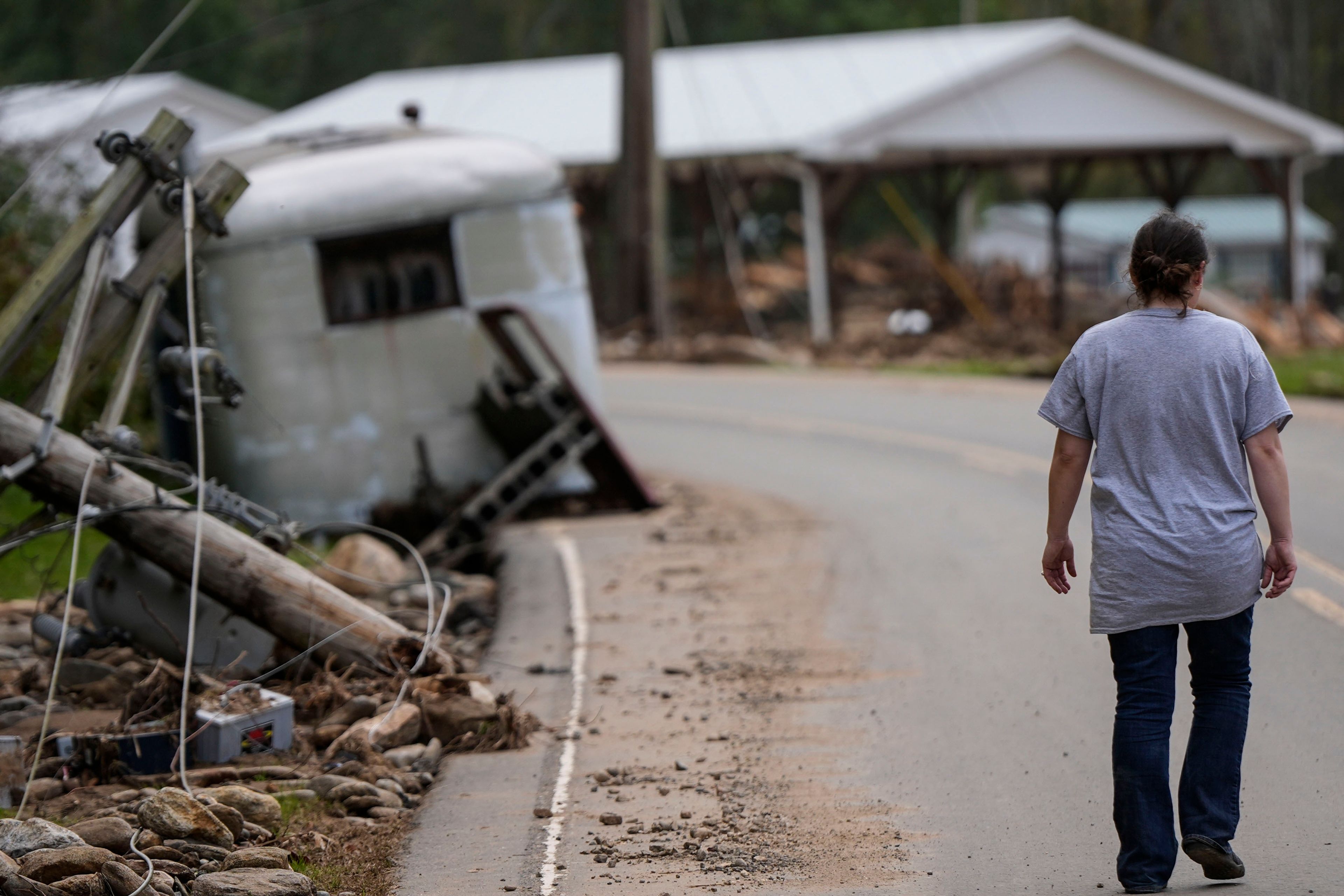 A woman walks to her damaged home in the aftermath of Hurricane Helene, Thursday, Oct. 3, 2024, in Pensacola, N.C. (AP Photo/Mike Stewart)