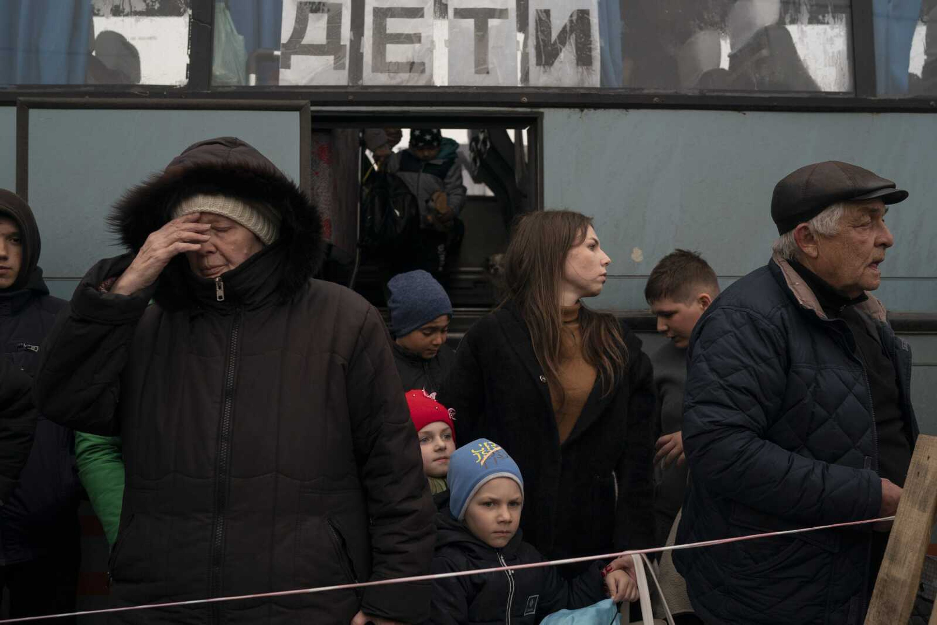 People from Mariupol and nearby towns step out of a bus, with a sign on the window that read in Russian: Children, and arrive Thursday at a refugee center fleeing from the war, in Zaporizhzhia, Ukraine. Mariupol, which is part of the industrial region in eastern Ukraine known as the Donbas, has been a key Russian objective since the Feb. 24 invasion began.