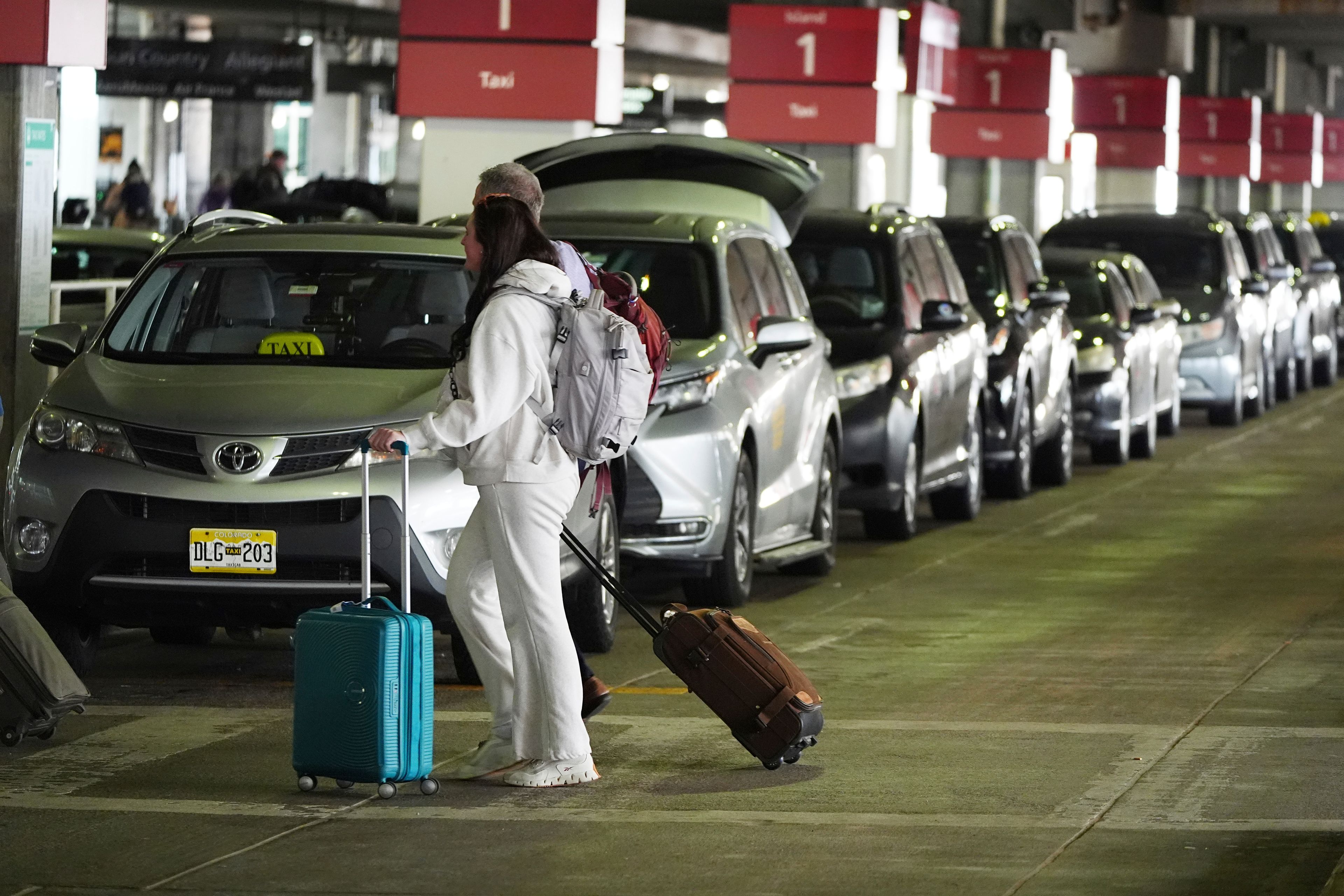 People pass by a long line of taxicabs at Denver International Airport Tuesday, Nov. 26, 2024, in Denver. (AP Photo/David Zalubowski)