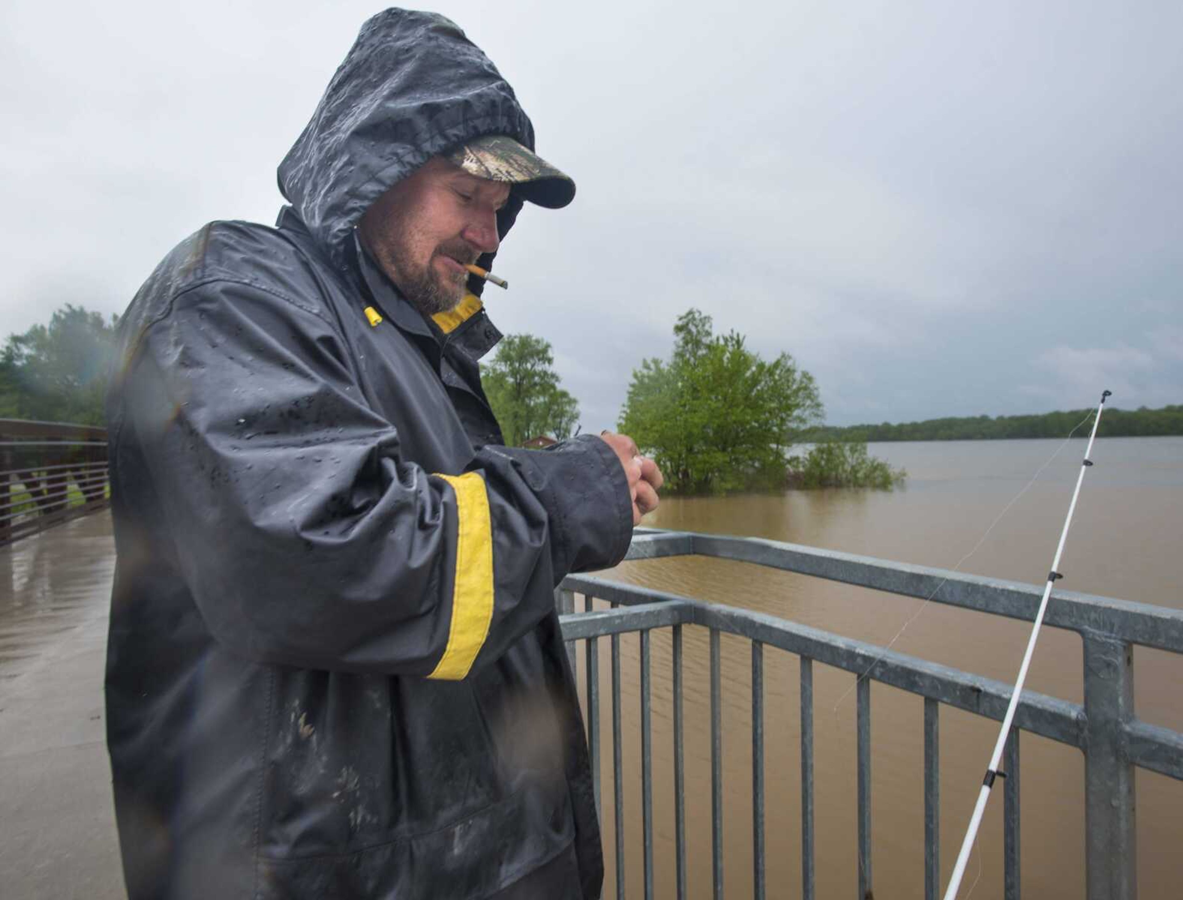 Brian Albright baits his fishing hook as floodwaters from the Mississippi River approach the Red Star District on Sunday in Cape Girardeau.