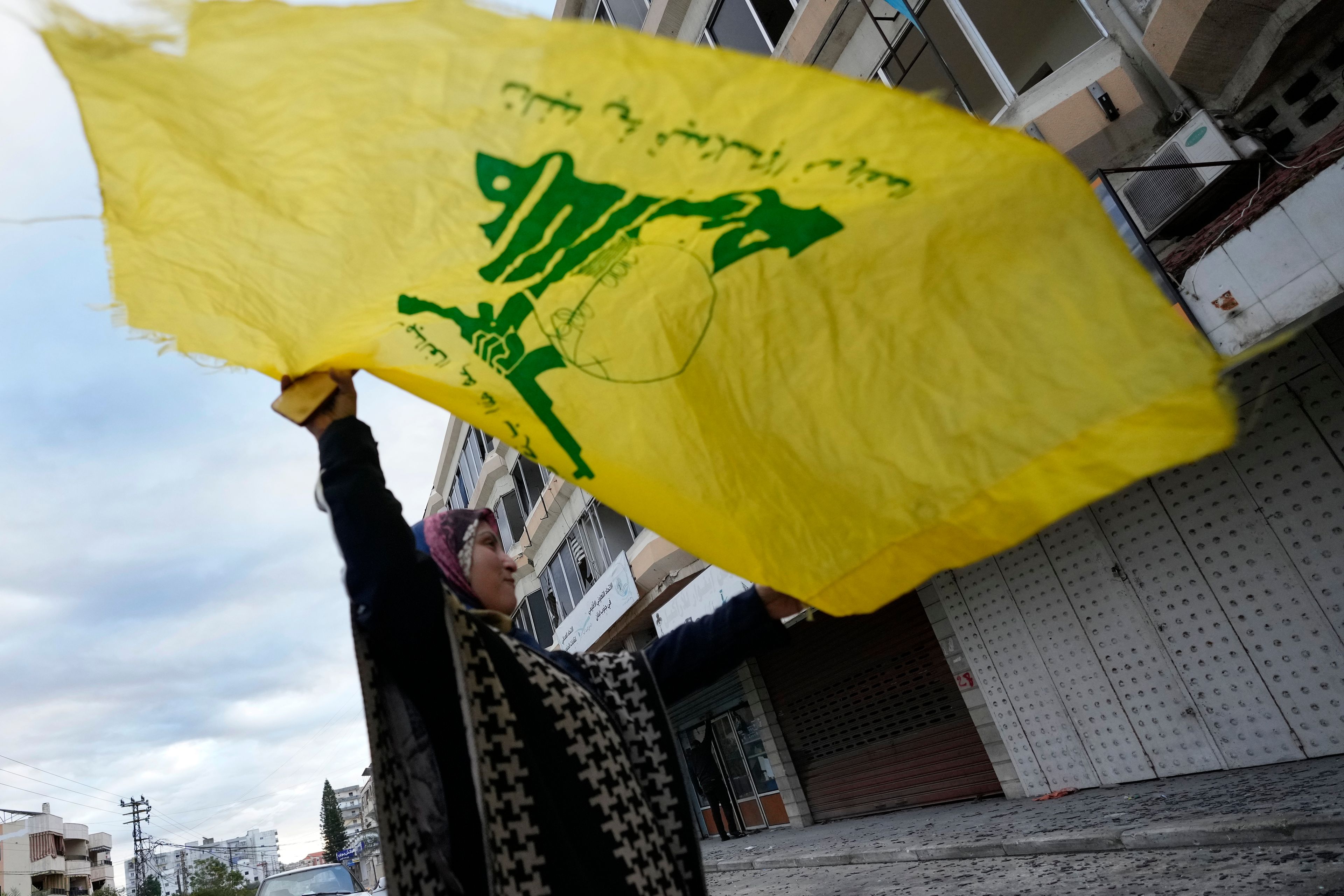 A woman waves a Hezbollah flag as she celebrates a ceasefire between Hezbollah and Israel which began early morning, in Tyre, south Lebanon, Wednesday, Nov. 27, 2024. (AP Photo/Hussein Malla)