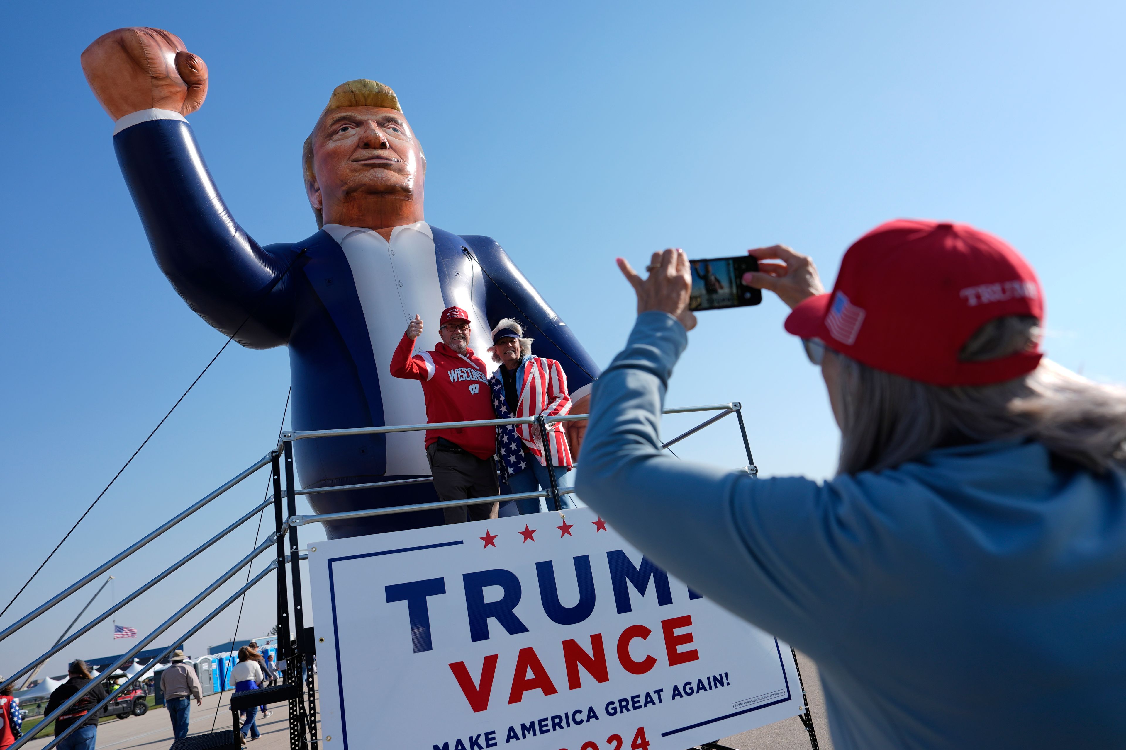 Supporters pose for a photo with an inflatable Donald Trump before a campaign rally for the Republican presidential nominee former President at Dodge County Airport, Sunday, Oct. 6, 2024, in Juneau, Wis. (AP Photo/Julia Demaree Nikhinson)