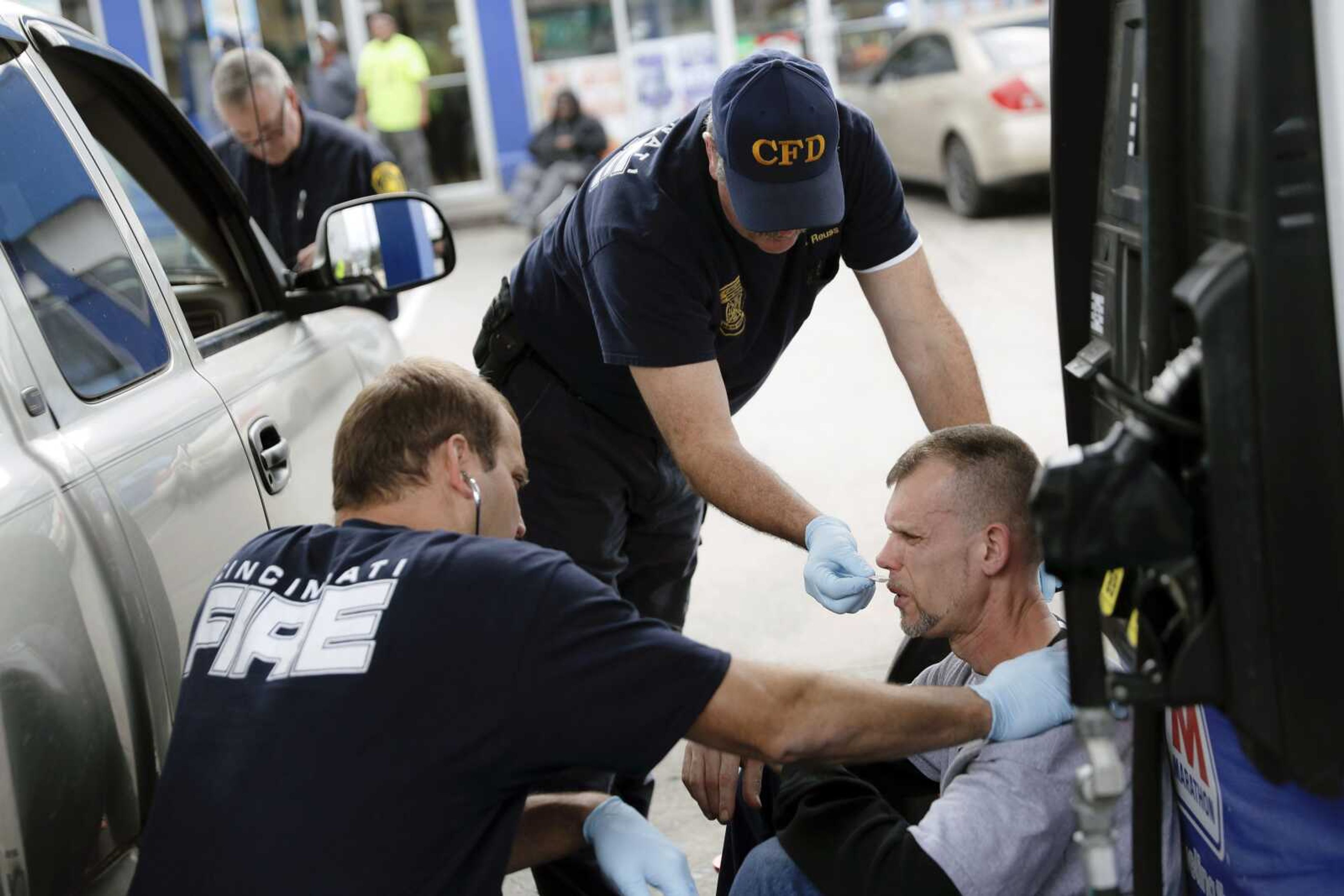 Medics with the Cincinnati Fire Department work to keep a possible overdose victim awake after administering Naloxone while responding to a call at a gas station in downtown Cincinnati.