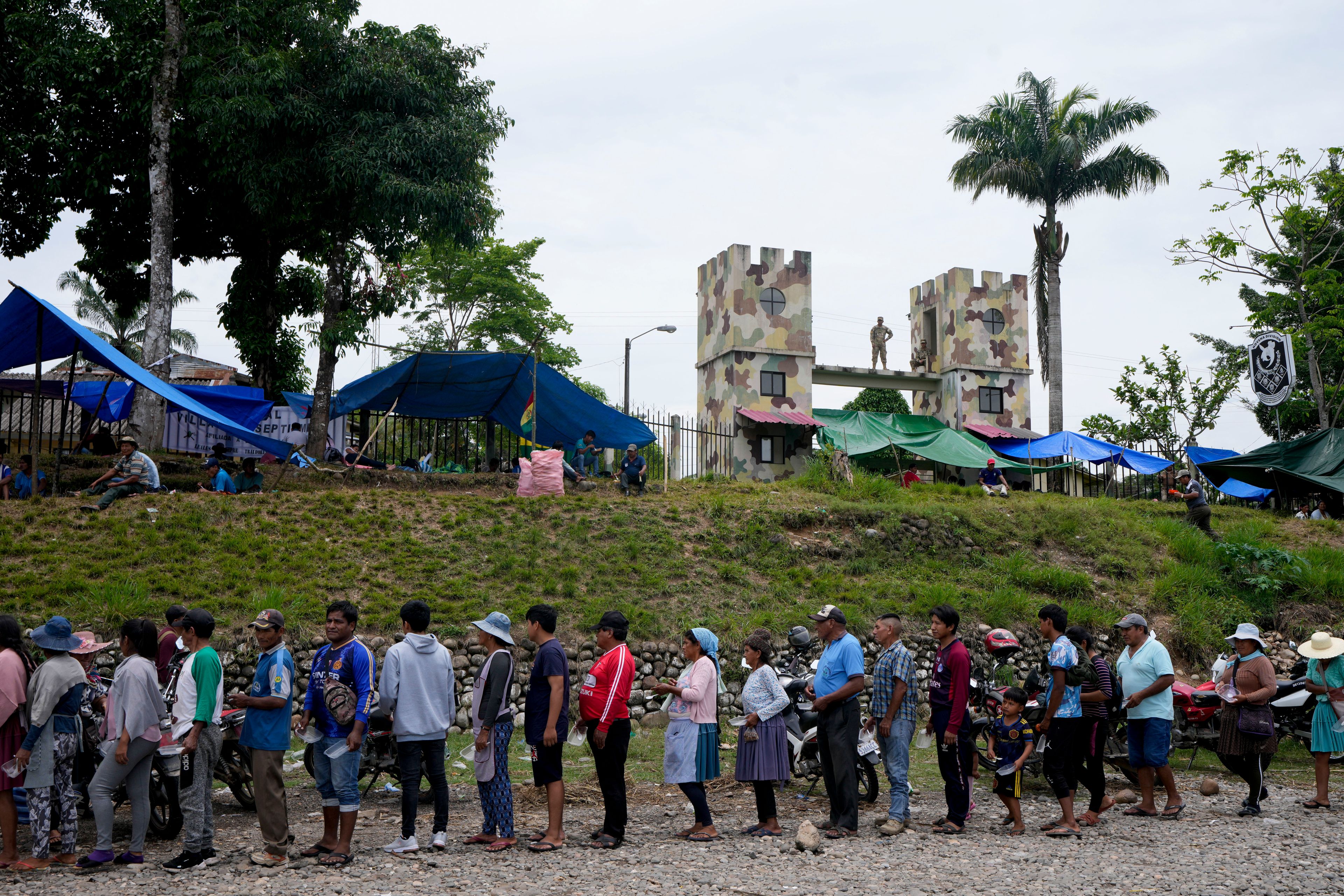 Followers of former President Evo Morales line up to receive food outside a military barracks in Shinahota, Chapare region, Bolivia, Sunday, Nov. 3, 2024, amid an ongoing political conflict between Morales and the government of President Luis Arce. (AP Photo/Juan Karita)