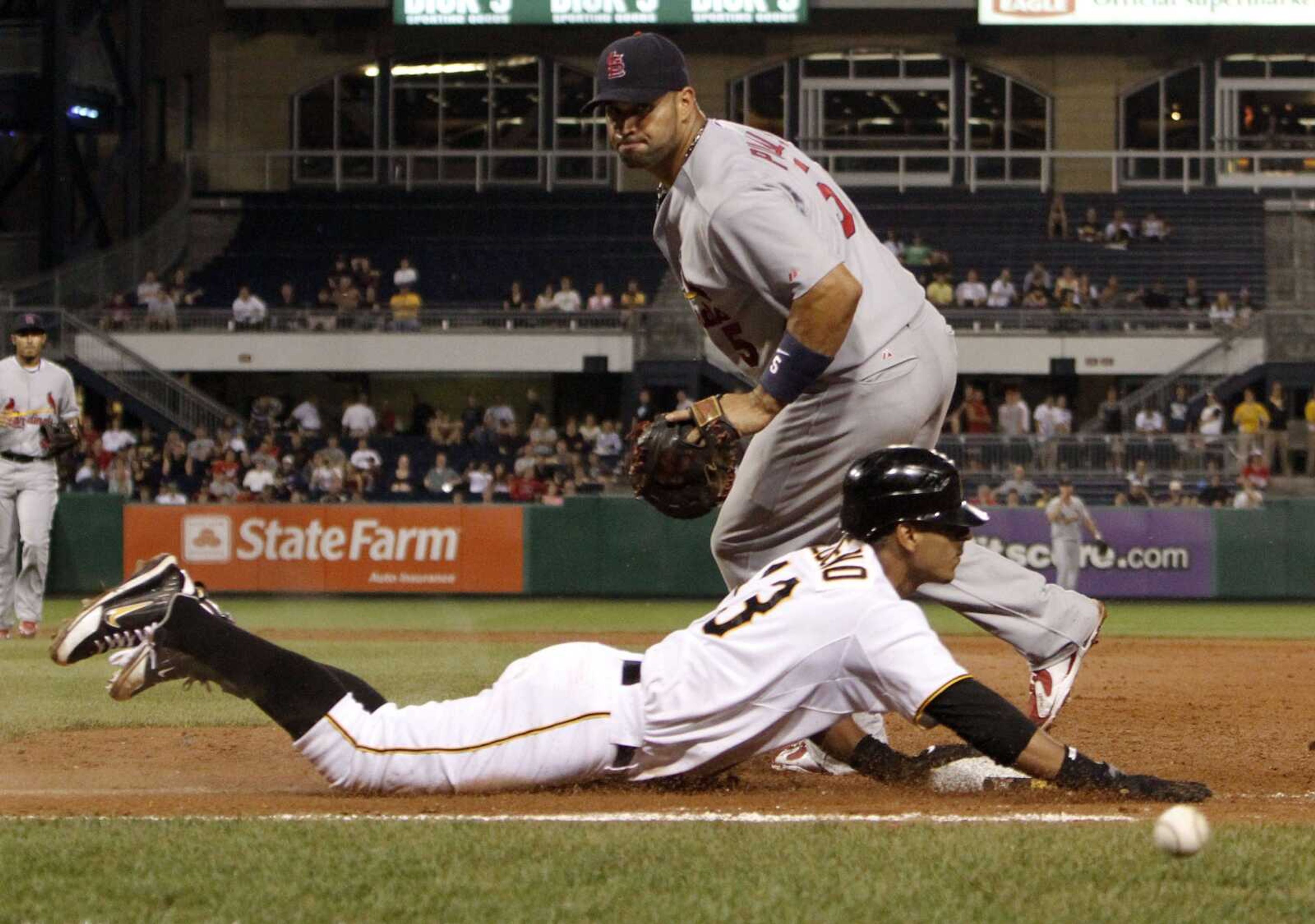 Pirates base runner Ronny Cedeno dives for first base as the ball gets away from Cardinals first baseman Albert Pujols during the eighth inning Wednesday in Pittsburgh. (KEITH SRAKOCIC ~ Associated Press)