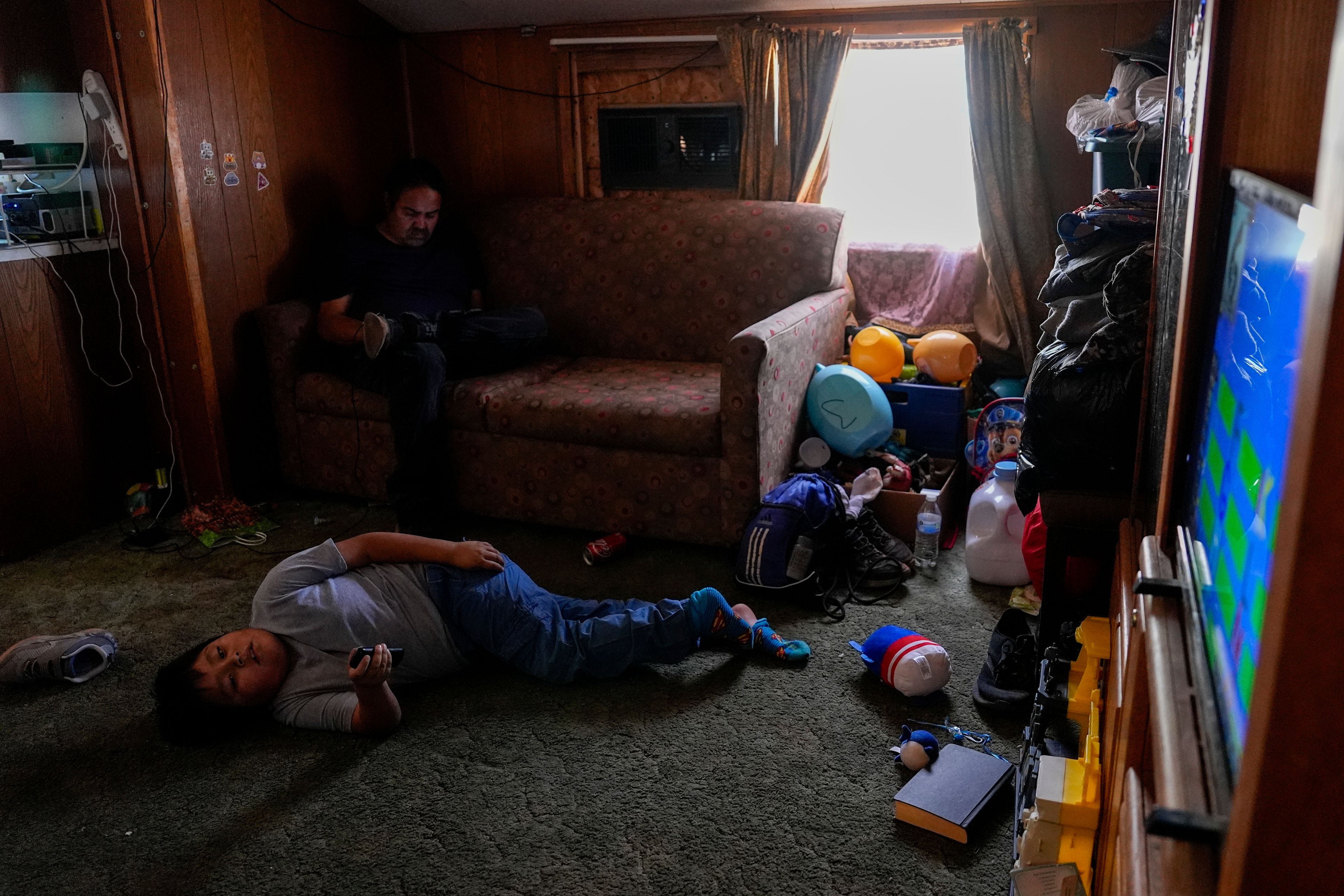 Liam Gillis, 7, relaxes after school with his grandfather, Ricky, top left, Wednesday, Oct. 9, 2024, at their home on the Navajo Nation in Halchita, Utah. (AP Photo/Joshua A. Bickel)