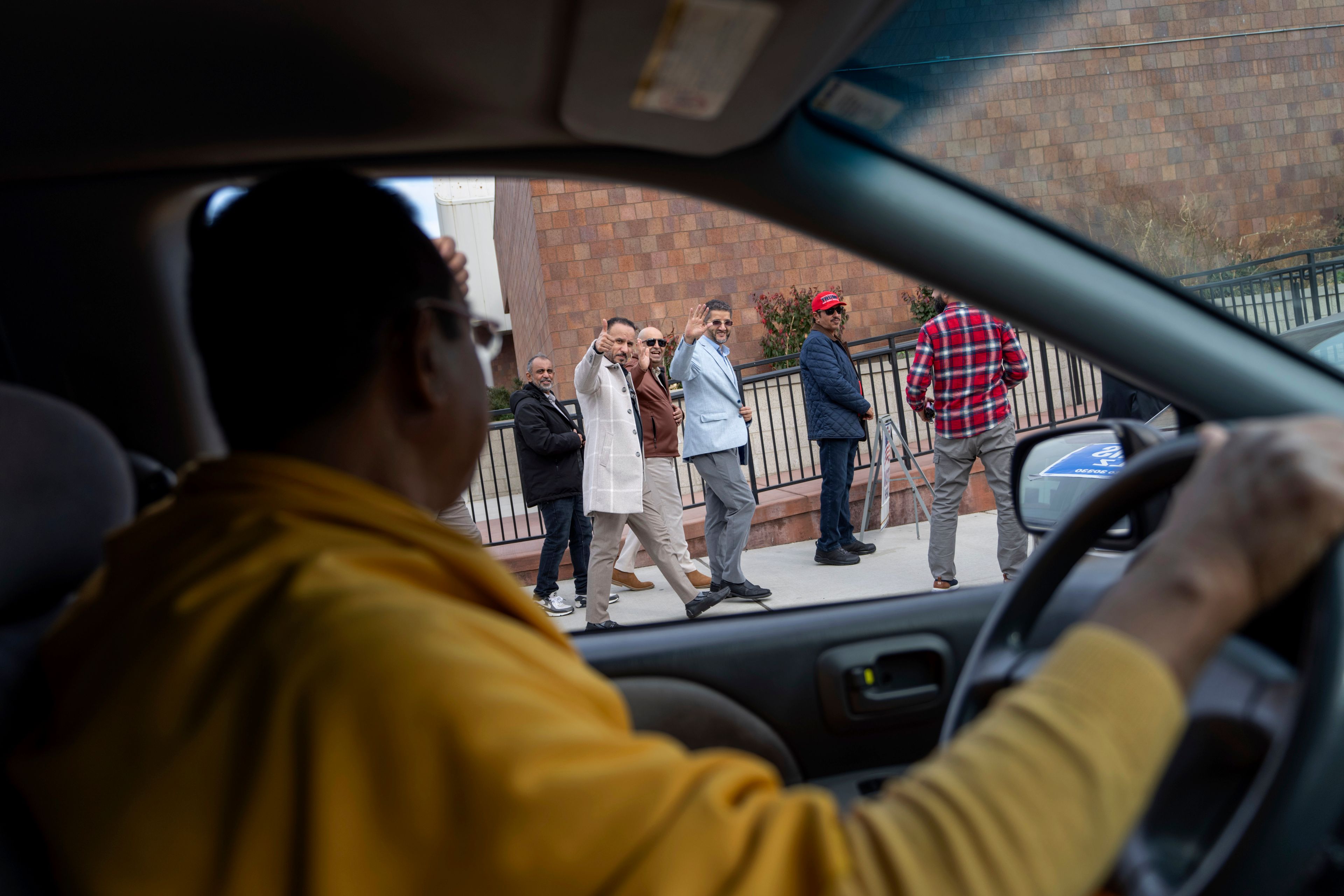 Dharmananda Mahaprabu Barua, a Buddhist monk and supporter of Republican presidential nominee former President Donald Trump, waves to Amer Ghalib, third from right, Hamtramck's Democratic Muslim mayor and fellow Trump supporter, as he drives through Hamtramck, Mich., on Election Day, Tuesday, Nov. 5, 2024. (AP Photo/David Goldman)