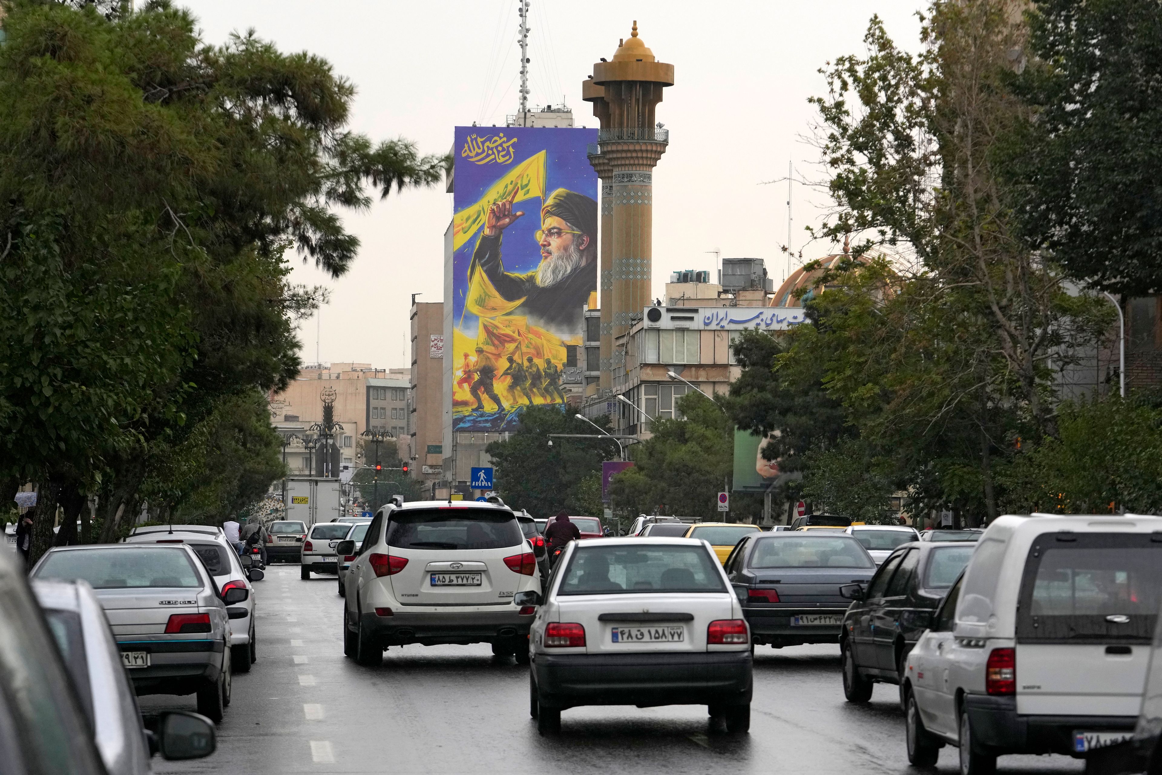 Vehicles drive under a huge portrait of slain Hezbollah leader Hassan Nasrallah, in downtown Tehran, Iran, Monday, Sept. 30, 2024. The billboard reads in Farsi on top left: "The beginning of Nasrallah." (AP Photo/Vahid Salemi)