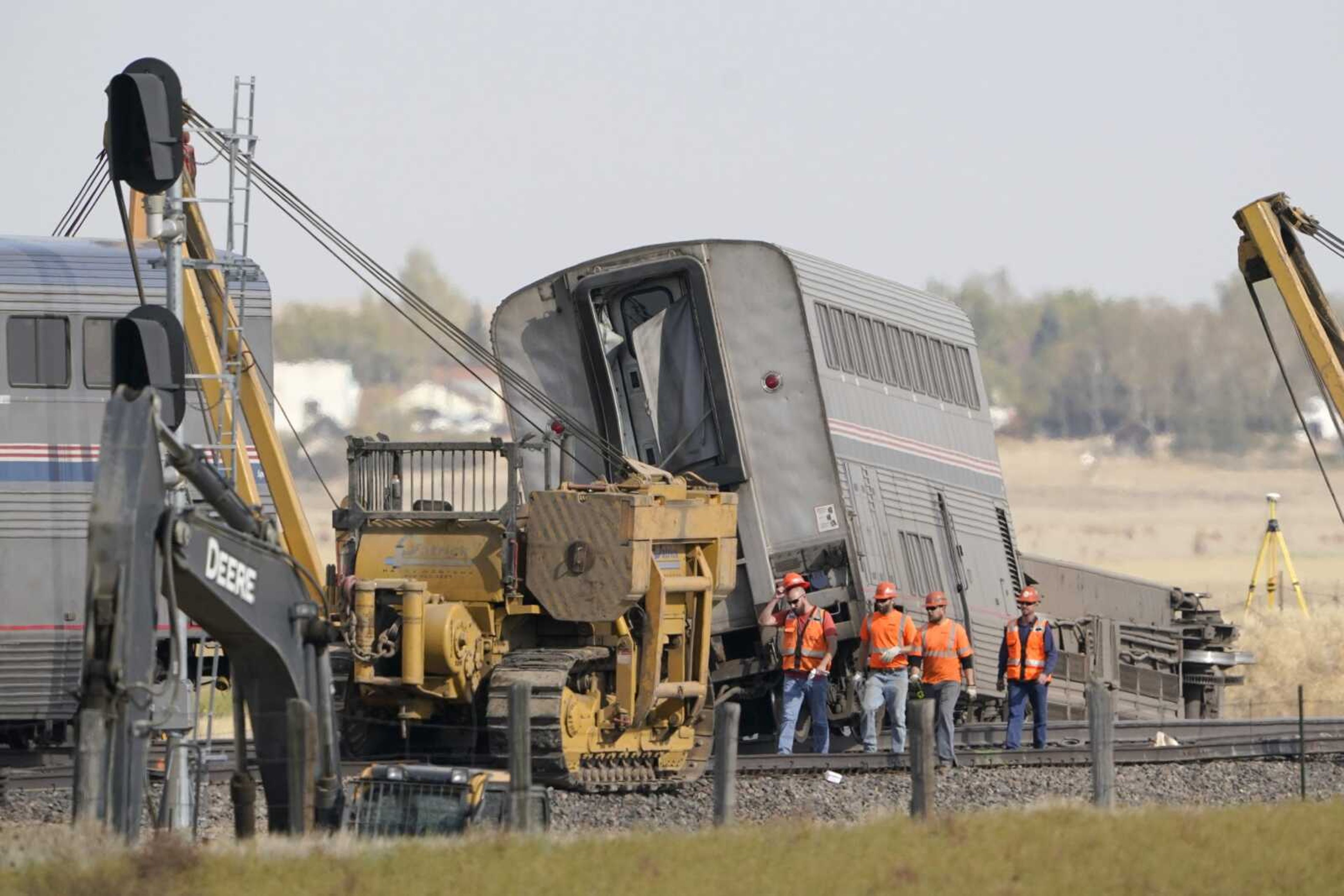 Workers walk Sunday next to an Amtrak train that derailed Saturday just west of Joplin, Montana.