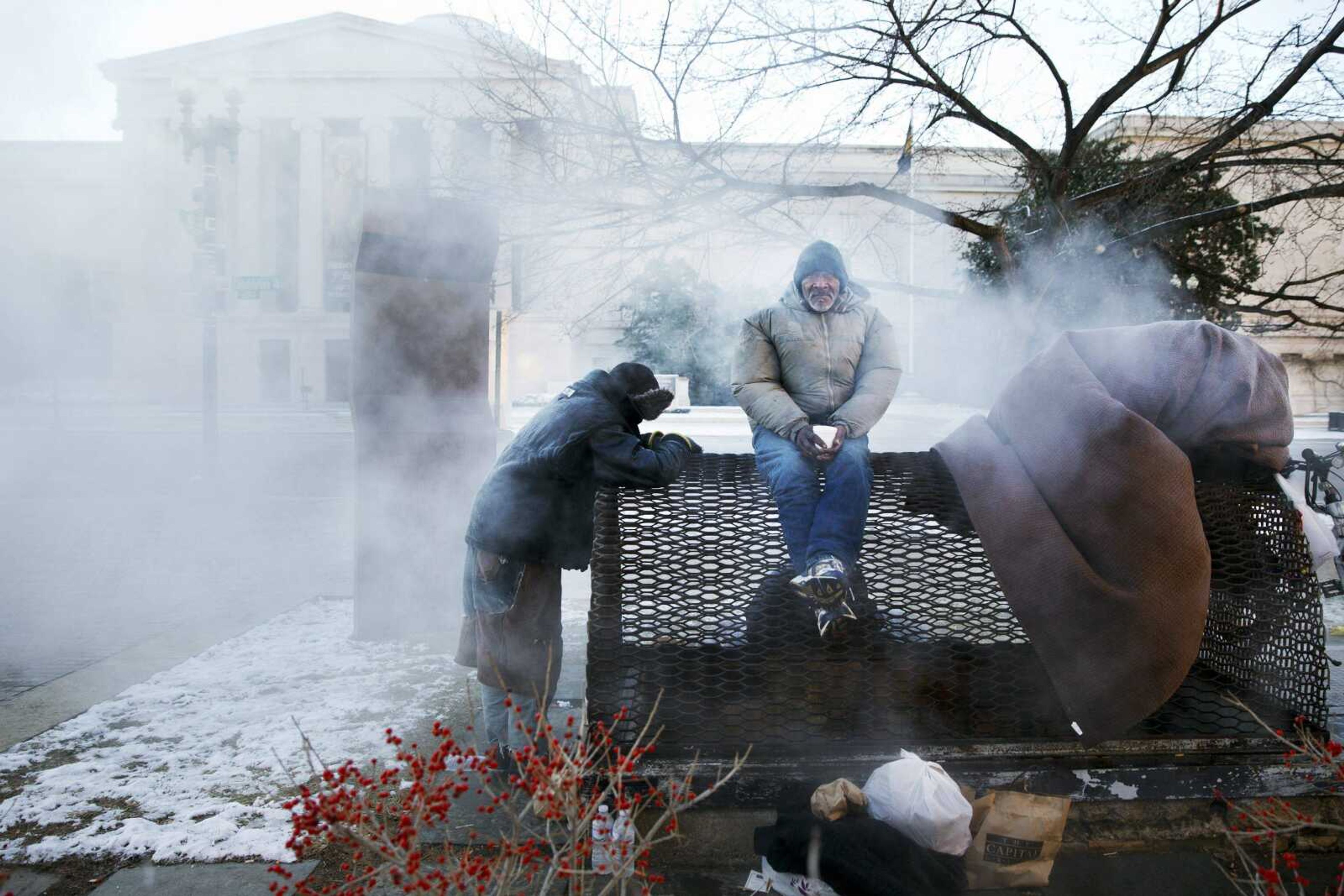 Four homeless men warm themselves on a steam grate by the Federal Trade Commission, blocks from the Capitol, during frigid temperatures in Washington, Saturday, January 4, 2014. A winter storm that swept across the Midwest this week blew through the Northeast on Friday, leaving bone-chilling cold in its wake. (AP Photo/Jacquelyn Martin)