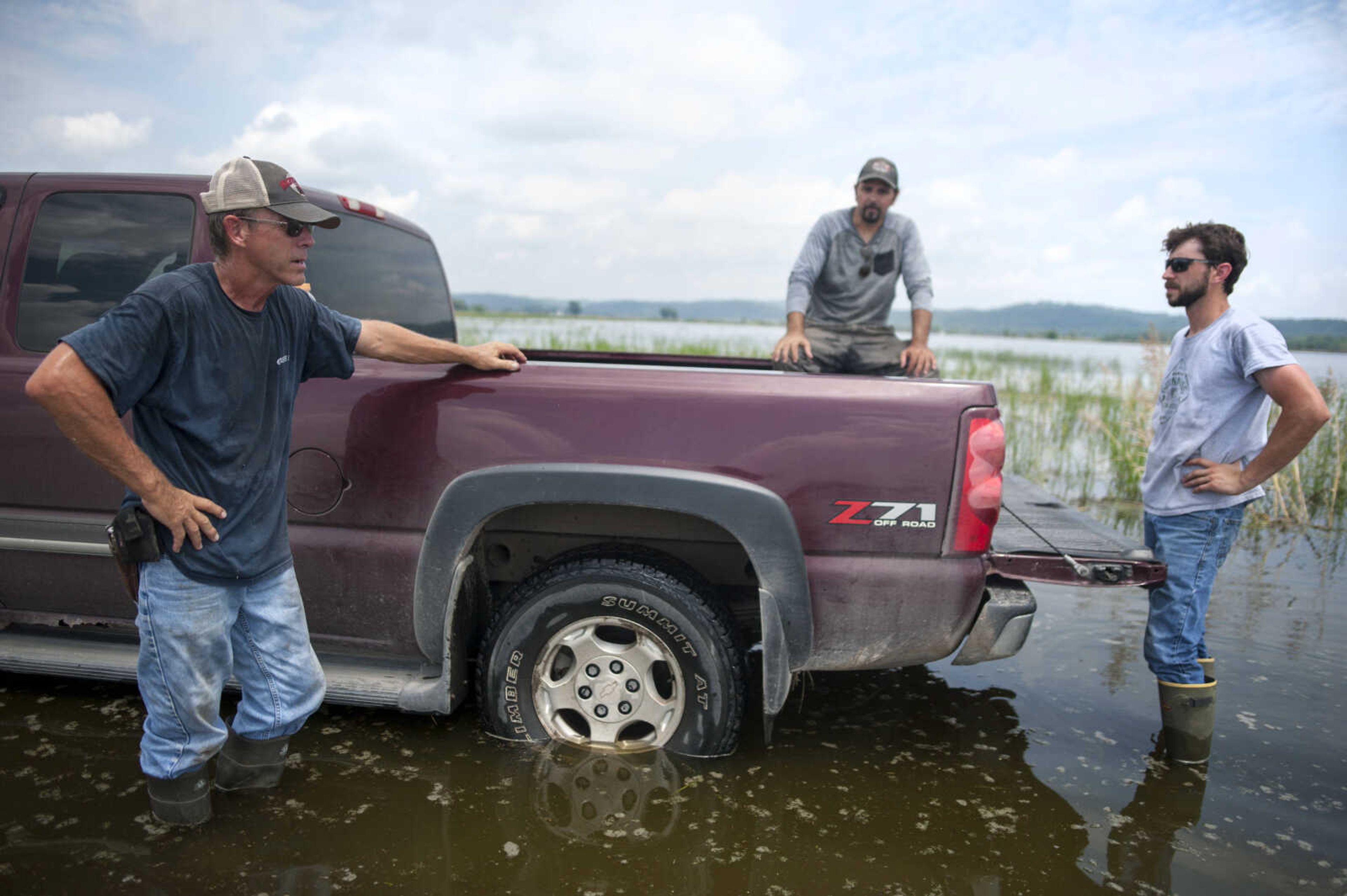 Charles Webb, left, talks with his son, Evan, far right, and Brian Winans after checking a flood gauge in one of his fields Saturday, July 6, 2019, in McClure. The most recent readings had measured about a half-inch daily rise, which Webb said was an improvement over the inch-a-day readings of a few days previously.