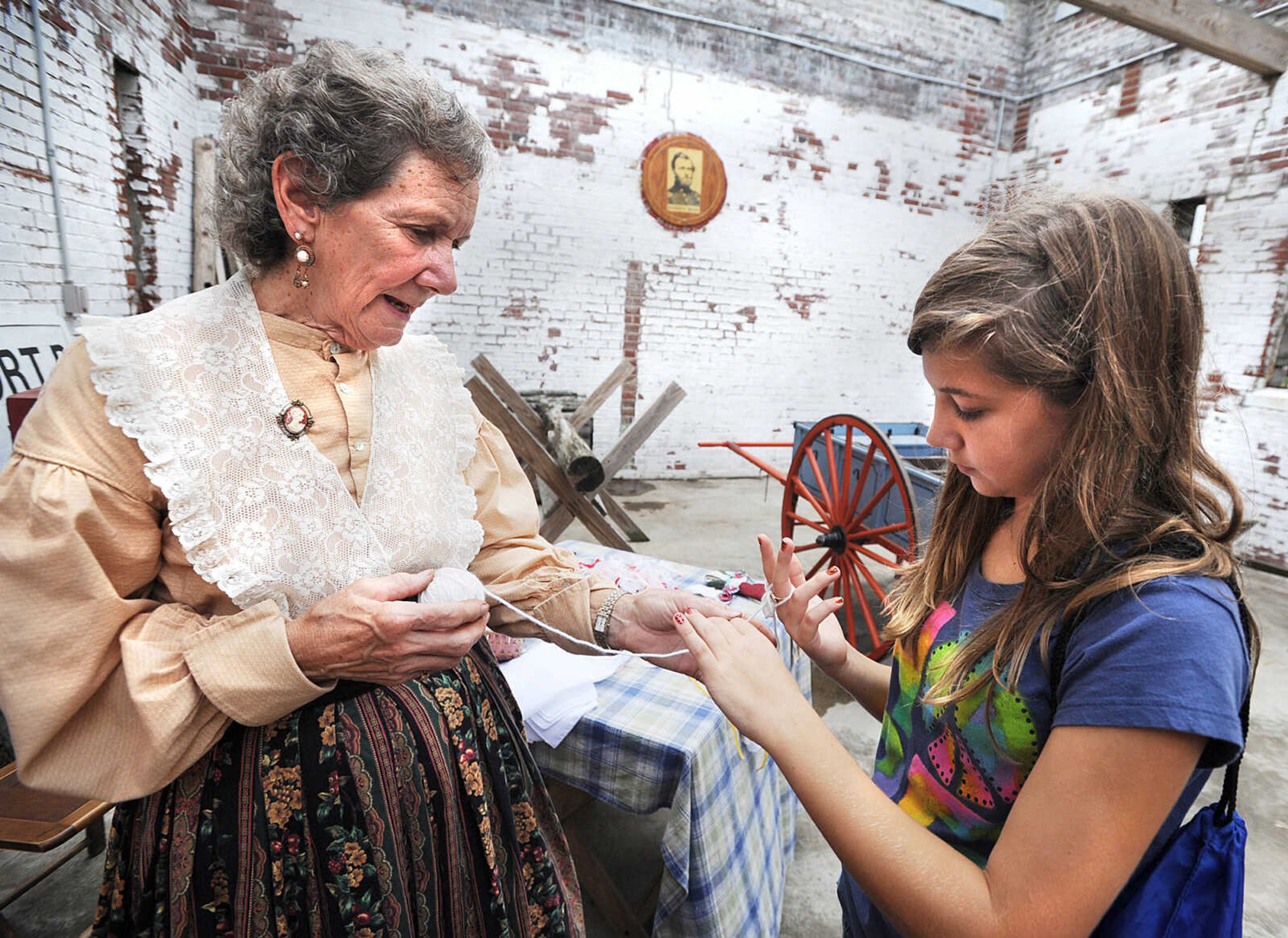 LAURA SIMON ~ lsimon@semissoruian.com
Emily Harris, right, shows Fort D re-enactor Pat Hagler how to create a bracelet using a finger weave Monday, Sept. 3, 2012 during Labor Day at Fort D in Cape Girardeau.