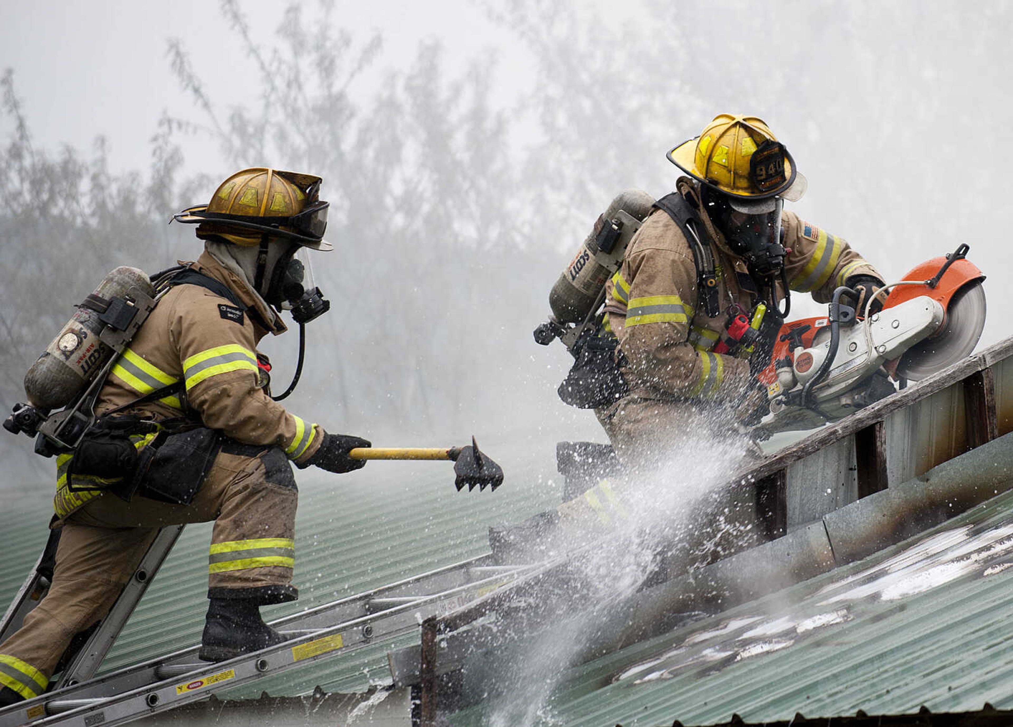 Cape Girardeau firefighters use a saw to cut through the roof as they battle a structure fire at 710 Morgan Oak  St., Tuesday, April 29, in Cape Girardeau. A Cape Girardeau Police officer saw the fire and called it in at 1:16 p.m. The building contained two apartments that were home to five people, though no one was home at the time of the fire. The cause of the fire is under investigation.