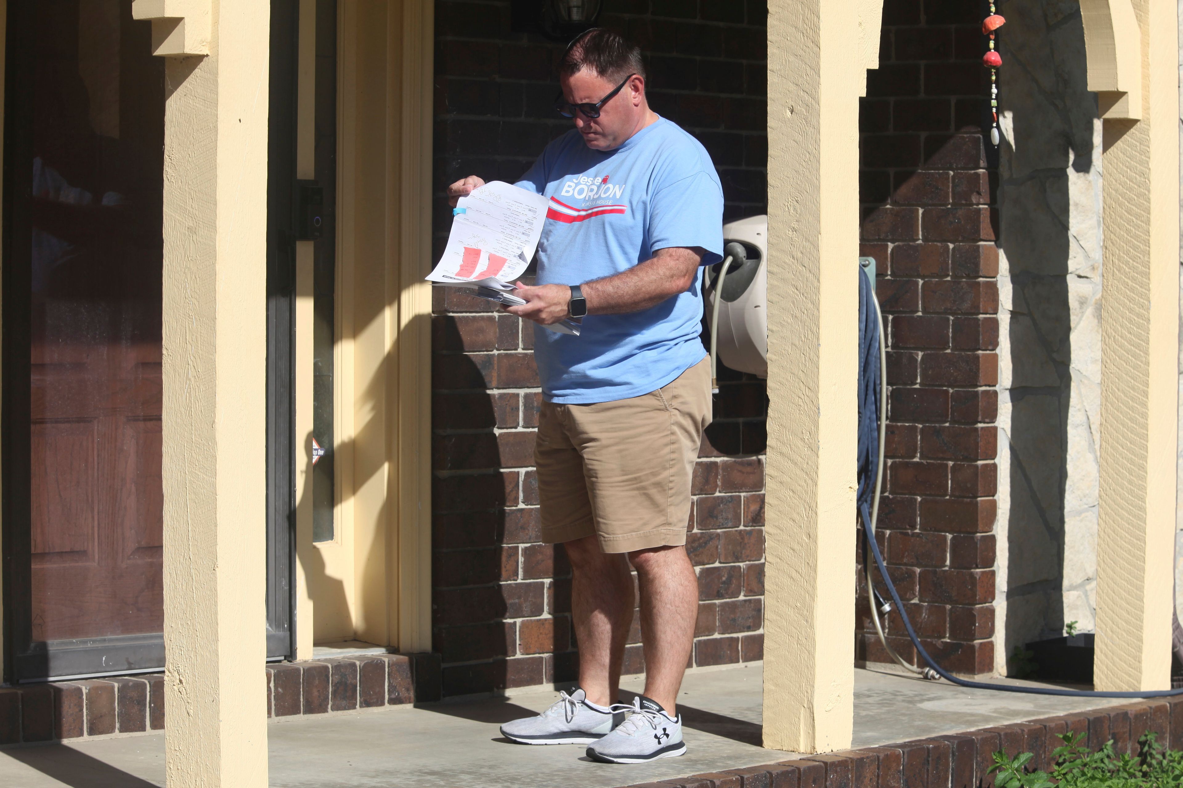 Kansas state Rep. Jesse Borjon, R-Topeka, checks a list of registered voters as he waits to see whether someone will answer their door as he campaigns, Saturday, Oct. 5, 2024, in Topeka, Kansas. (AP Photo/John Hanna)