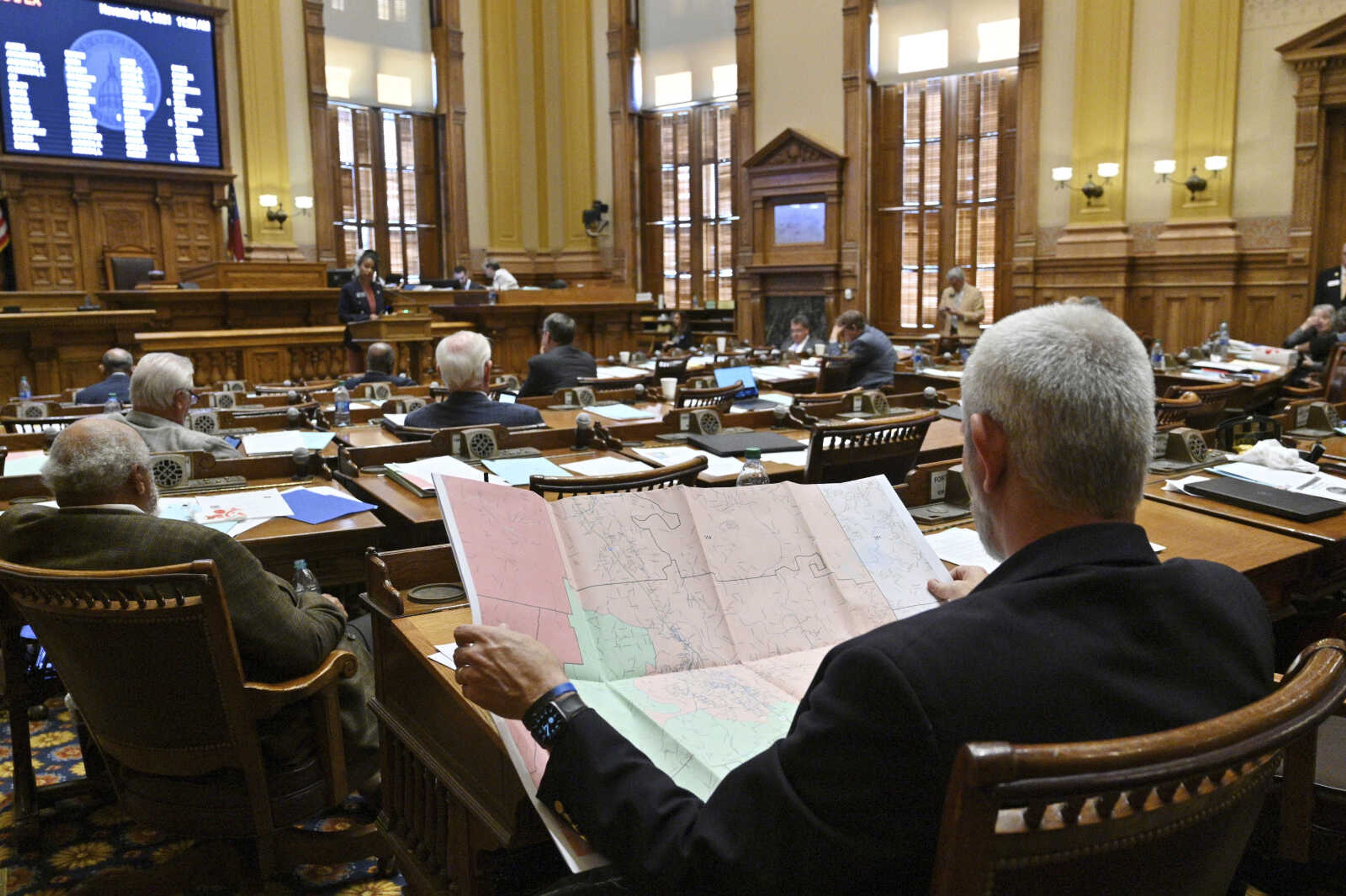 FILE - Georgia Sen. Chuck Payne, R-Dalton, foreground, looks at a map as Sen. Nikki Merritt, D-Grayson, background, speaks in opposition of Senate Bill 2EX, newly drawn congressional maps, in the Senate Chambers during a special session at the state Capitol, Nov. 19, 2021, in Atlanta. Lawyers for the state said on Wednesday, Nov. 1, 2023, that it wouldn t appeal a ruling ordering the maps to be redrawn, but wouldn t seek to freeze the ruling during the appeal. (Hyosub Shin/Atlanta Journal-Constitution via AP, File)