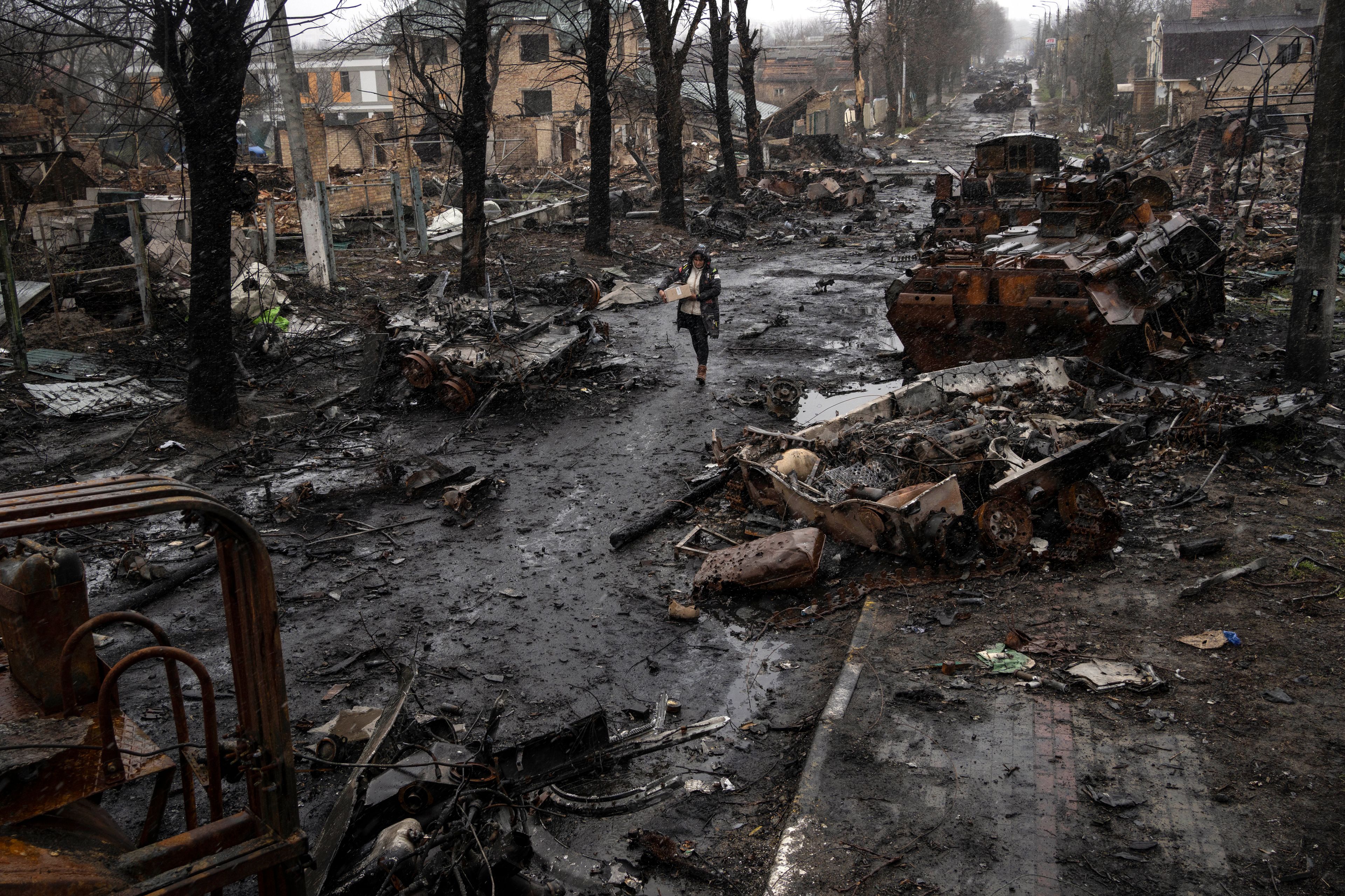 FILE - A woman walks amid destroyed Russian tanks in Bucha, in the outskirts of Kyiv, Ukraine, Sunday, April 3, 2022. (AP Photo/Rodrigo Abd, File)