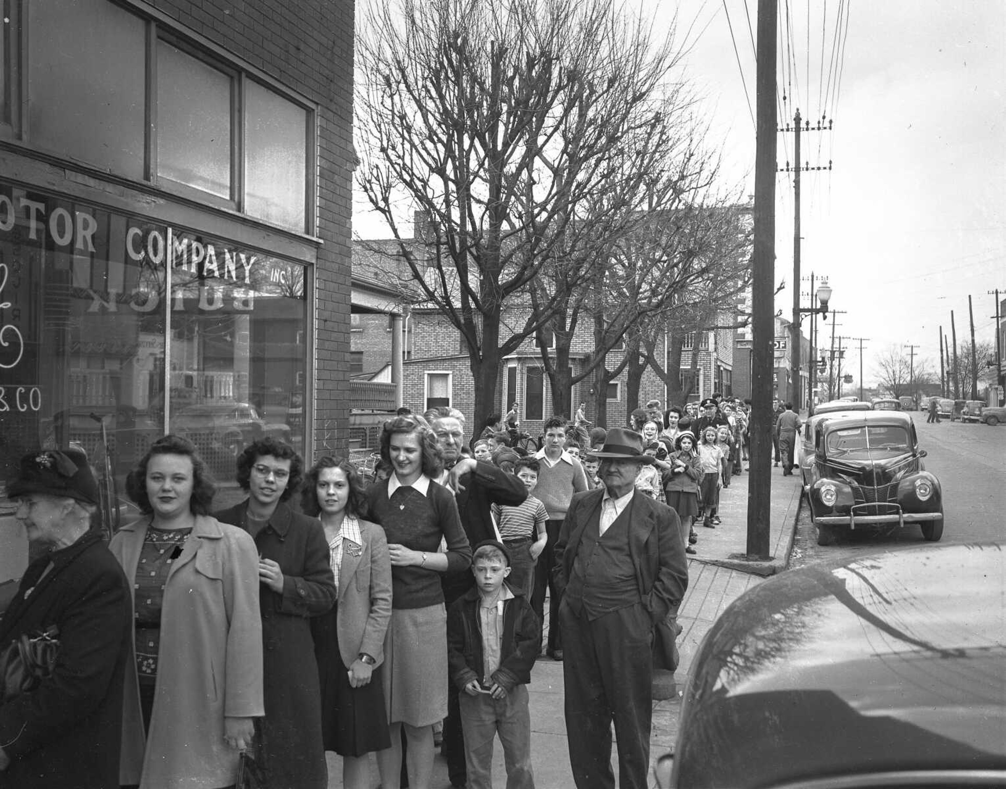 A hungry line of customers waits to sample the products turned out by the Lions Club during their annual Pancake Day in 1947. This photo was taken at the height of the noon rush hour in front of the Millikan Motor Co. salesroom, where the event was held.