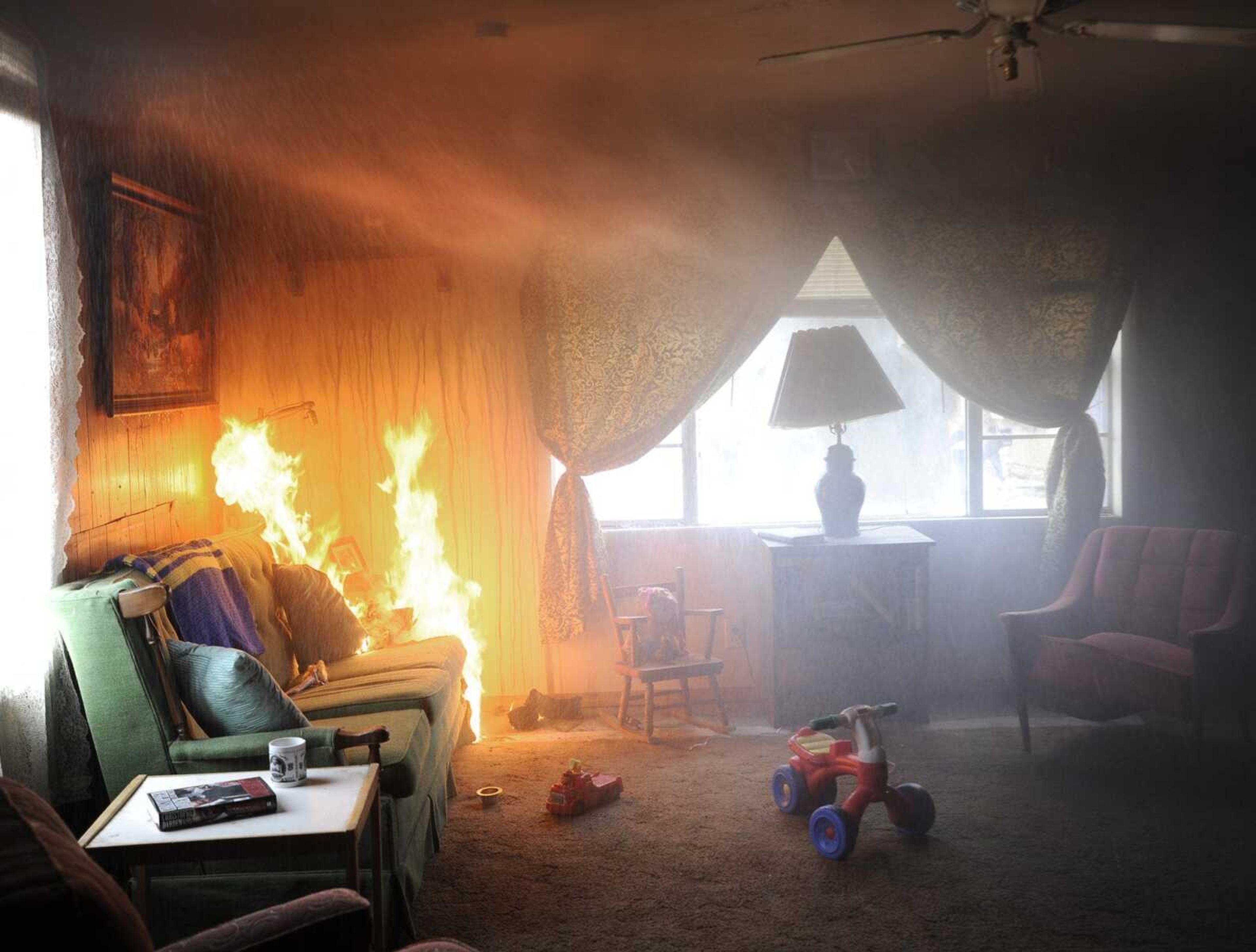 A fire sprinkler head activates above a burning sofa during a controlled burn demonstration Friday at a house on Spanish Street in Cape Girardeau. (Fred Lynch)