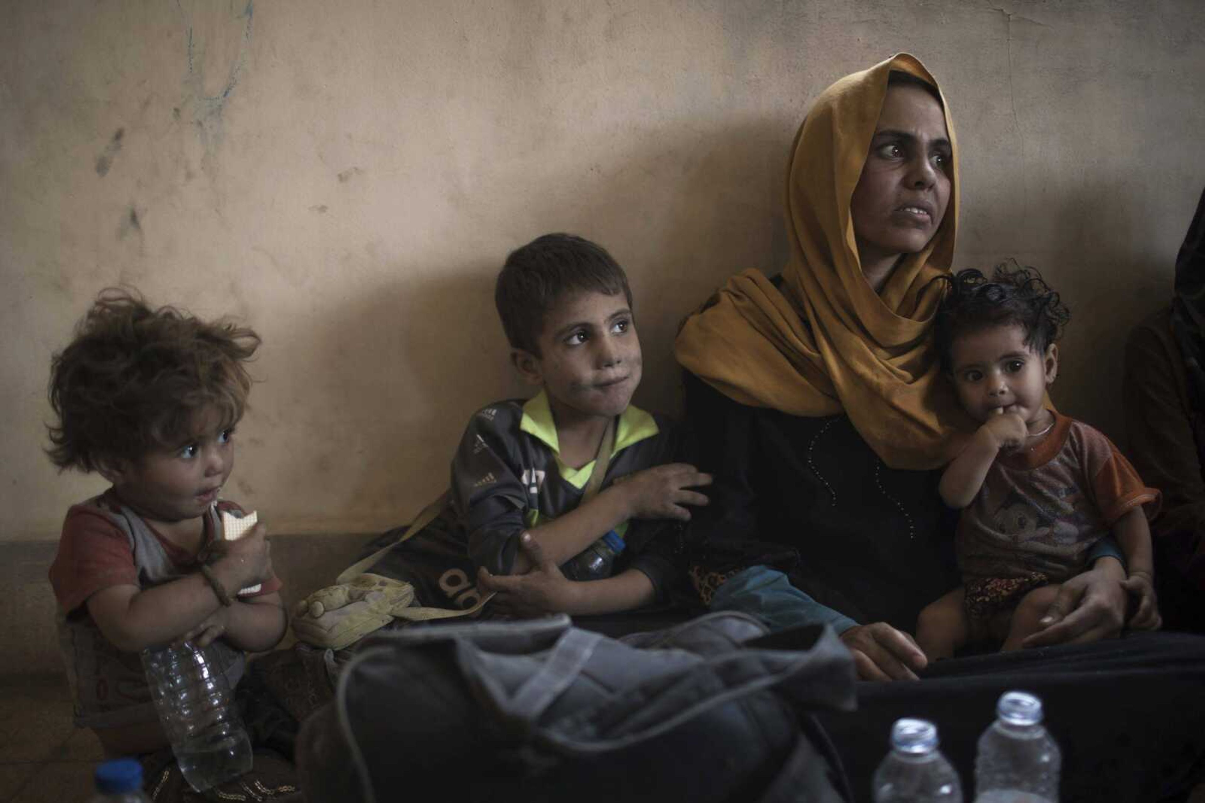 Iraqi civilians sit inside a house as they wait to be taken out of the Old City during fighting Sunday between Iraqi forces and Islamic State militants in Mosul, Iraq.