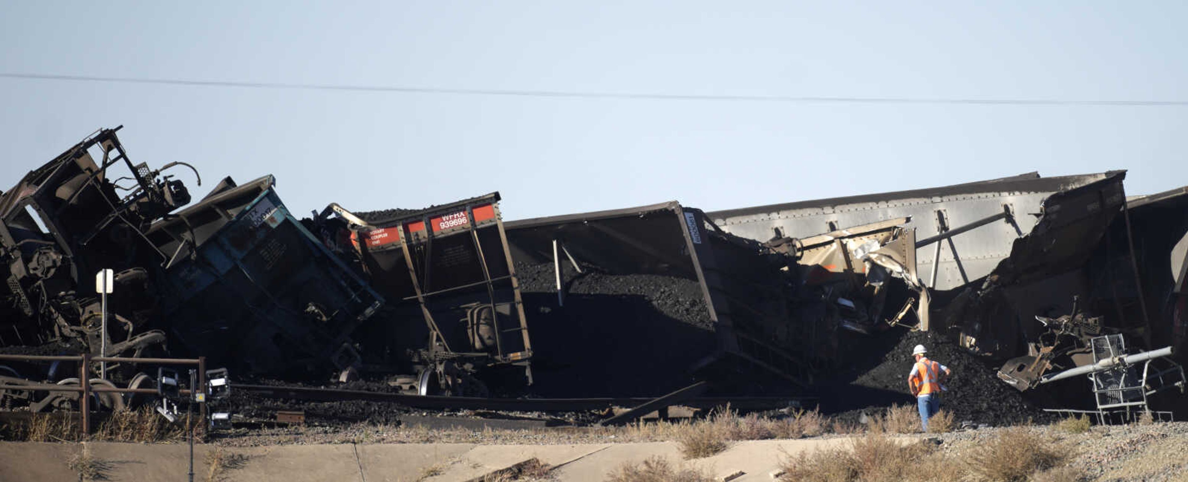 A worker observes cars that derailed in an accident over Interstate 25 northbound, Monday, Oct. 16, 2023, north of Pueblo, Colo. (AP Photo/David Zalubowski)