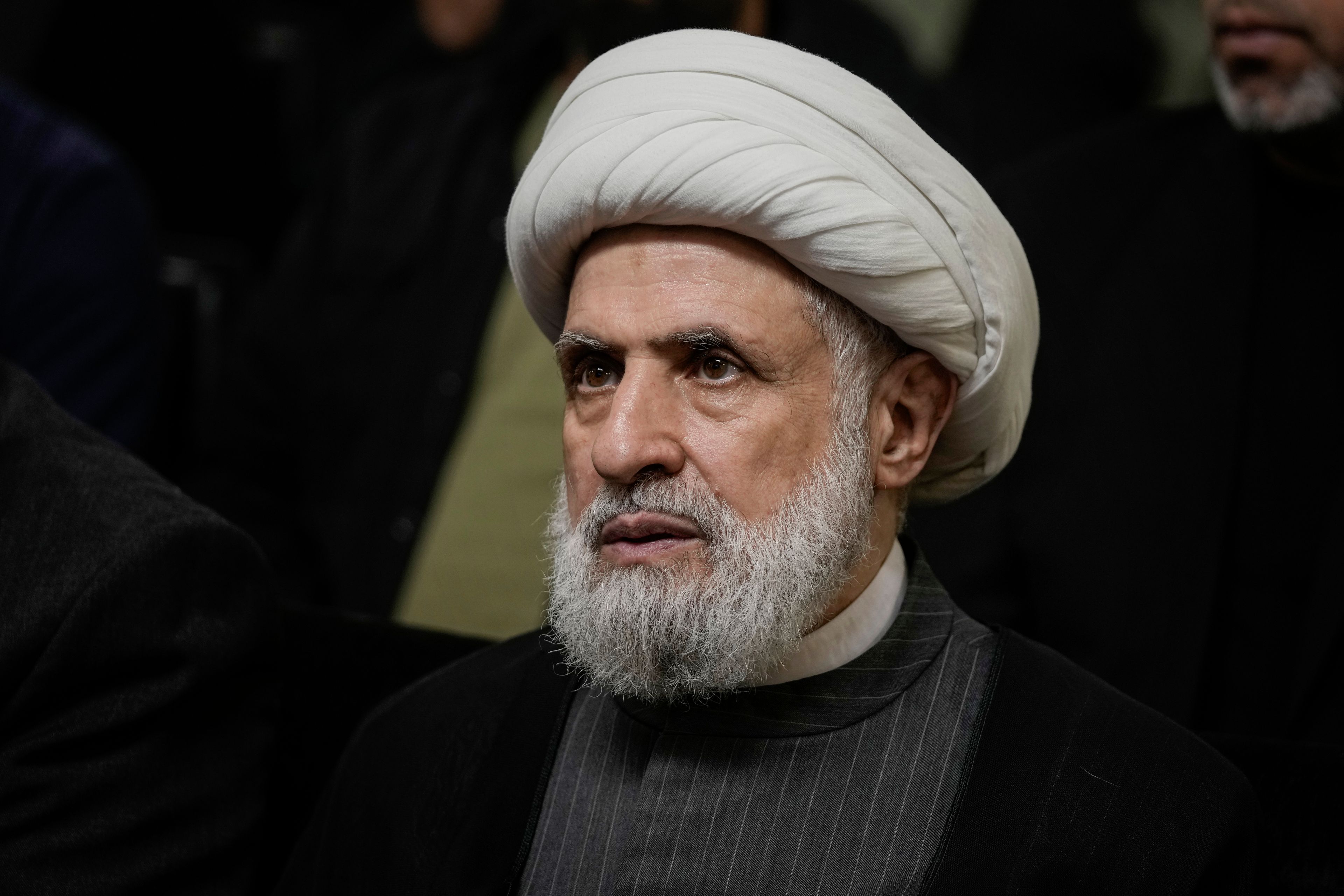 FILE - Hezbollah's deputy leader, Sheikh Naim Kassem, listens to a speech by then-leader Hassan Nasrallah on a screen in southern Beirut, Wednesday, June 19, 2024. (AP Photo/Bilal Hussein, File)