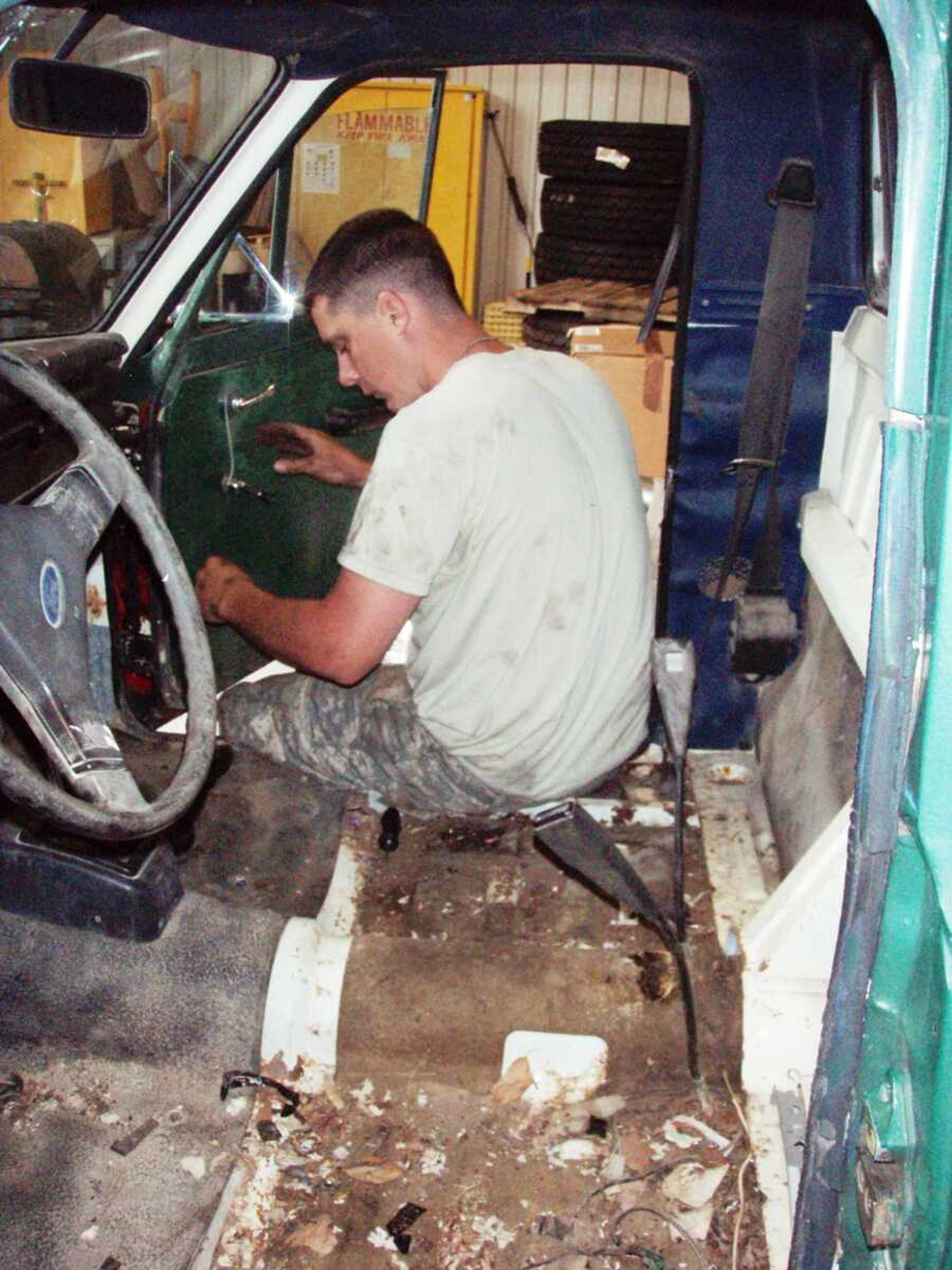 Spc. Justin Jordan of California, Mo., works on a civilian vehicle to get it running for a simulated training to teach MPs how to deal with approaching cars that may be occupied by hostiles.