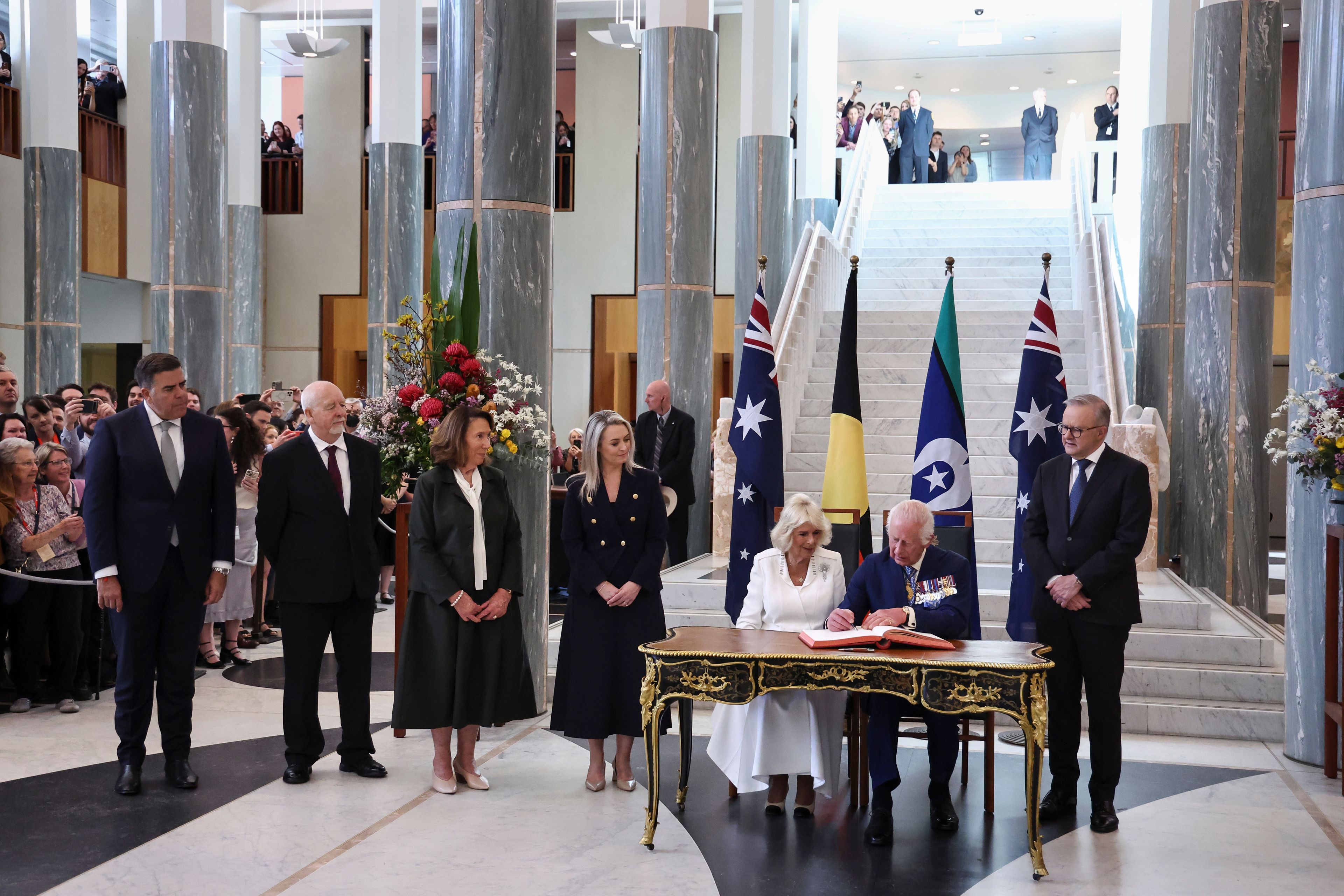 Britain's King Charles III and Queen Camilla sign a visitors' book in the Marble Foyer of Parliament House in Canberra, Australia, Monday, Oct. 21, 2024. (David Gray/Pool Photo via AP)