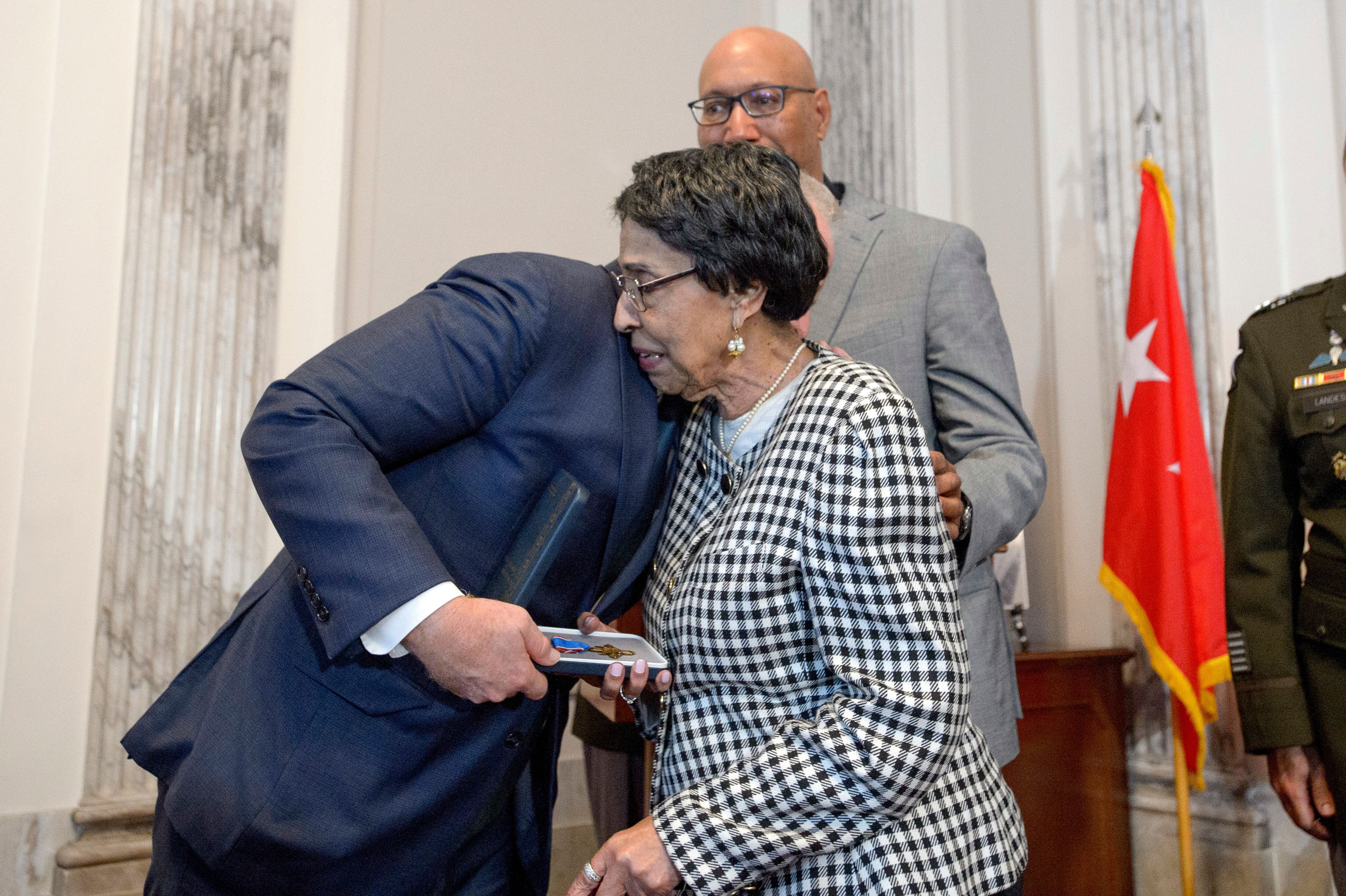 Sen. Chris Van Hollen, D-Md., left, presents the Distinguished Service Cross to Joann Woodson, center, and her son Steve Woodson, right, during a ceremony to posthumously award the Distinguished Service Cross to her husband U.S. Army Staff Sgt. Waverly Woodson, Jr., a medic who was part of the only Black combat unit to take part in the D-Day invasion of France during World War II, on Capitol Hill, in Washington, Tuesday, Sept. 24, 2024. (AP Photo/Rod Lamkey, Jr.)