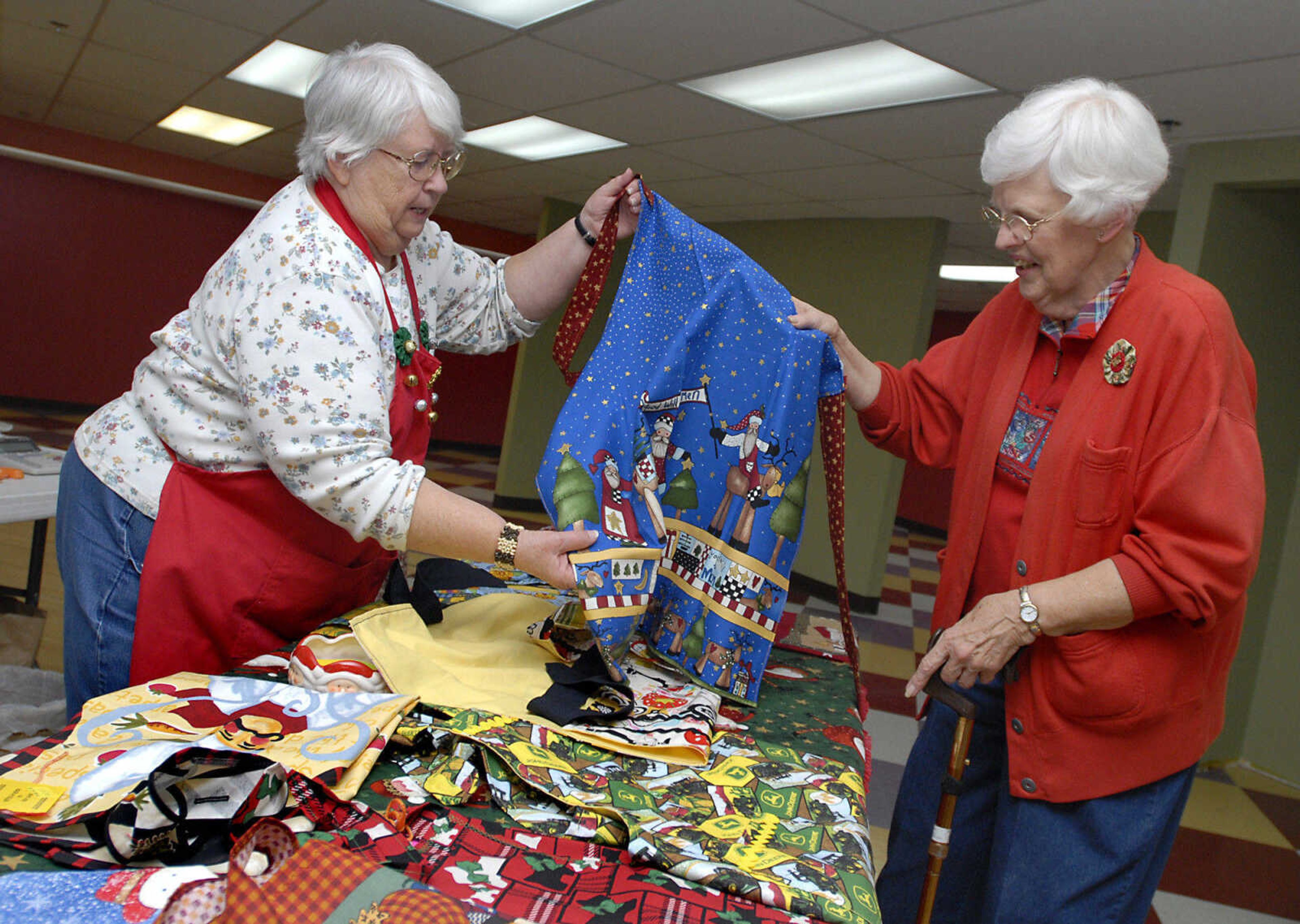 KRISTIN EBERTS ~ keberts@semissourian.com

Marjorie Suedekum, right, looks at some aprons made by Beverly Lewis, of "Stitch-A-Roos" during a craft fair sponsored by the Golden Needle in Cape Girardeau on Saturday, Nov. 19, 2011.