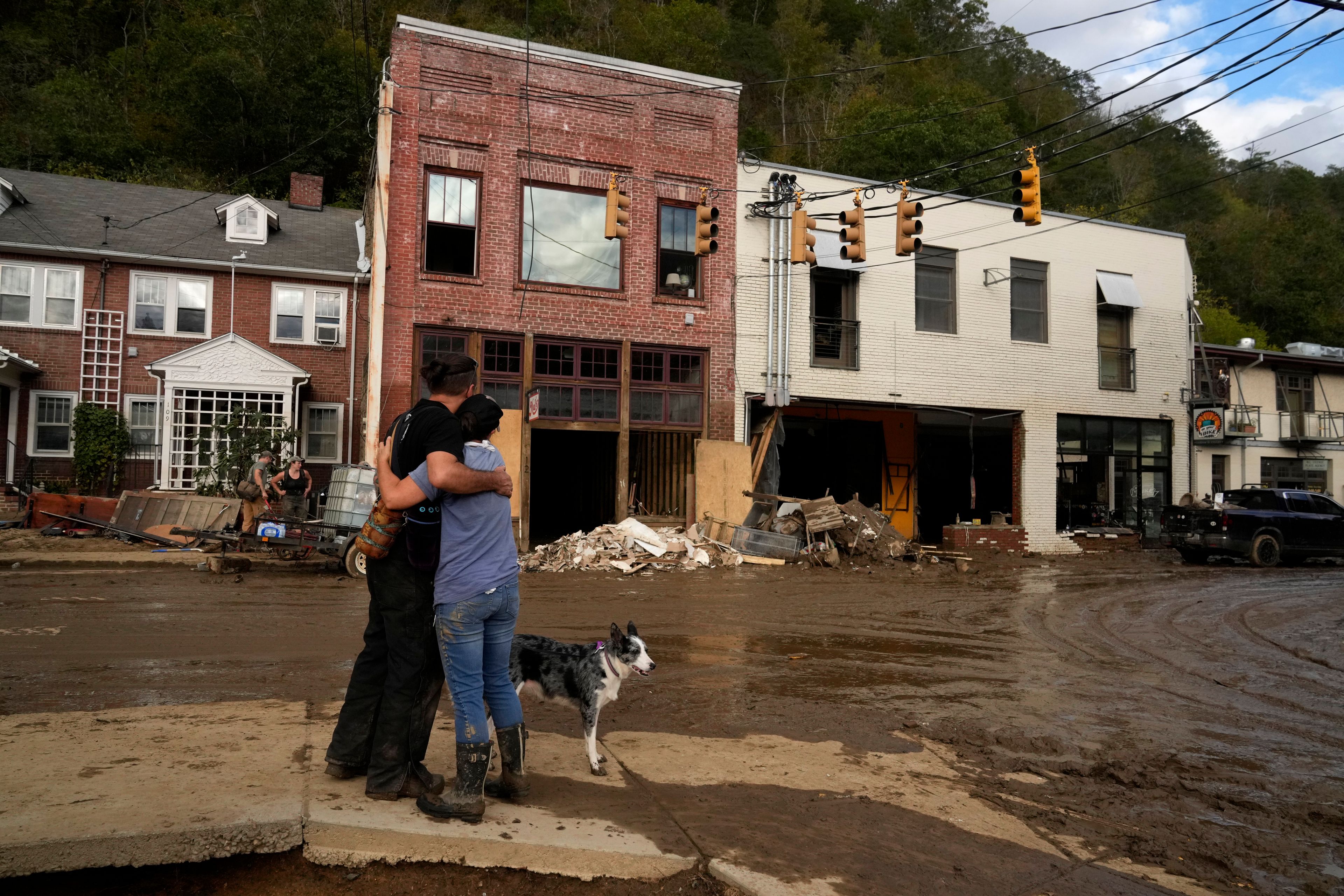 Resident Anne Schneider, right, hugs her friend Eddy Sampson as they survey damage left in the wake of Hurricane Helene, Tuesday, Oct. 1, 2024, in Marshall, N.C. (AP Photo/Jeff Roberson)