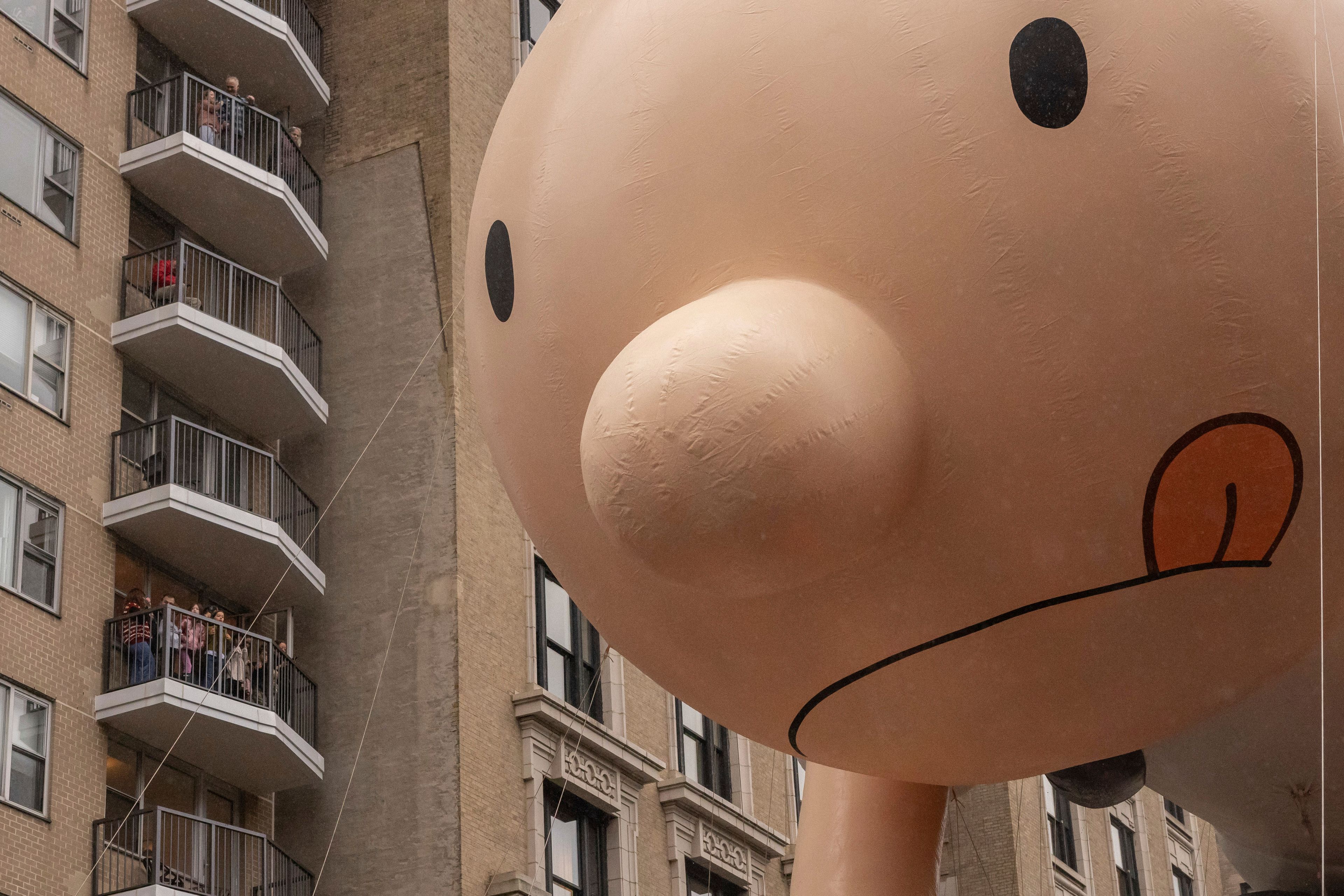 Spectators watch from a balcony as the balloon floats by along Central Park West during the Macy's Thanksgiving Day parade, Thursday, Nov. 28 2024, in New York. (AP Photo/Yuki Iwamura)