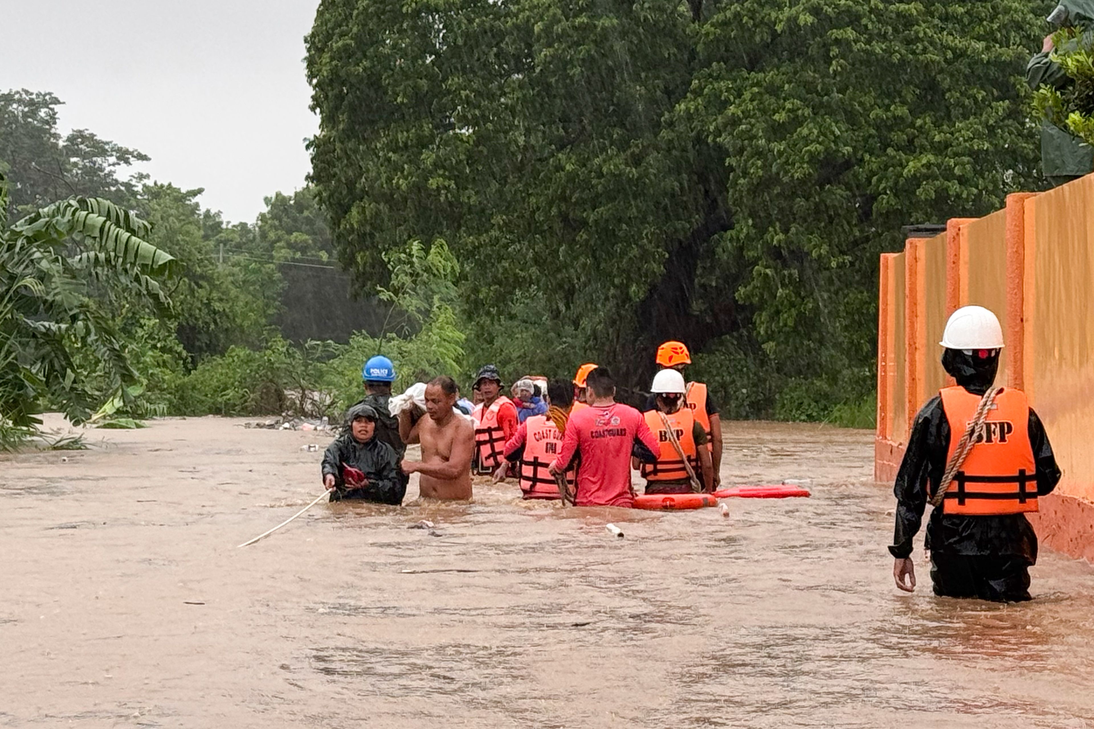 Rescuers help residents as they negotiate floods caused by powerful Typhoon Krathon locally called "Typhoon Julian" at Bacarra, Ilocos Norte province, northern Philippines on Monday, Sept. 30, 2024. (AP Photo/Bernie Dela Cruz)