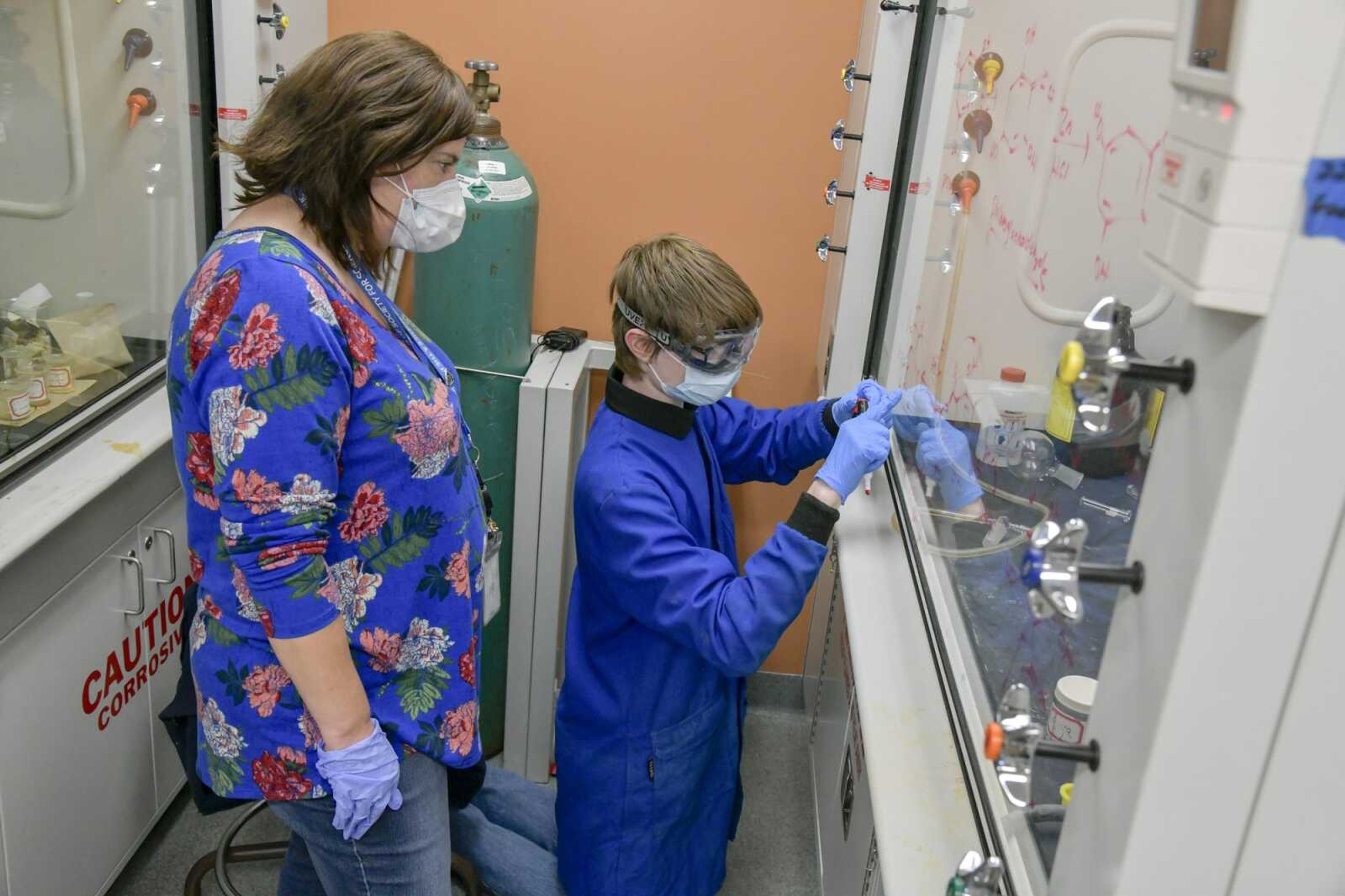 From left, science teacher Leanne Thele listens as student Elijah Jones reviews details of his research project on a fume hood in a Southeast Missouri State University laboratory on Dec. 1, 2020.