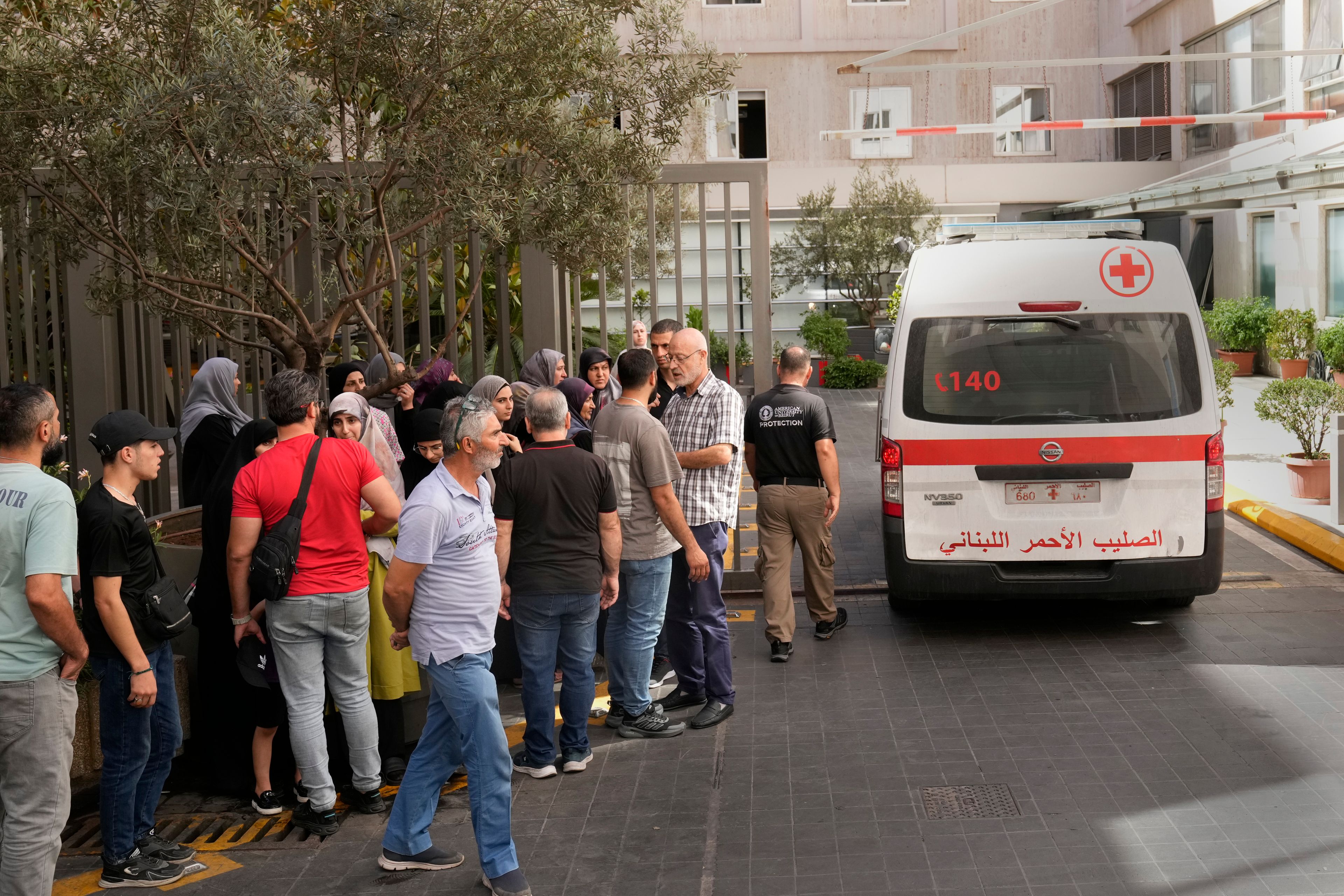 CORRECTS DAY TO TUESDAY WHEN INJURED Lebanese Red Cross ambulance passes next of the families of victims who were injured on Tuesday by their exploding handheld pagers, at the emergency entrance of the American University hospital, in Beirut, Lebanon, Wednesday, Sept. 18, 2024. (AP Photo/Hussein Malla)