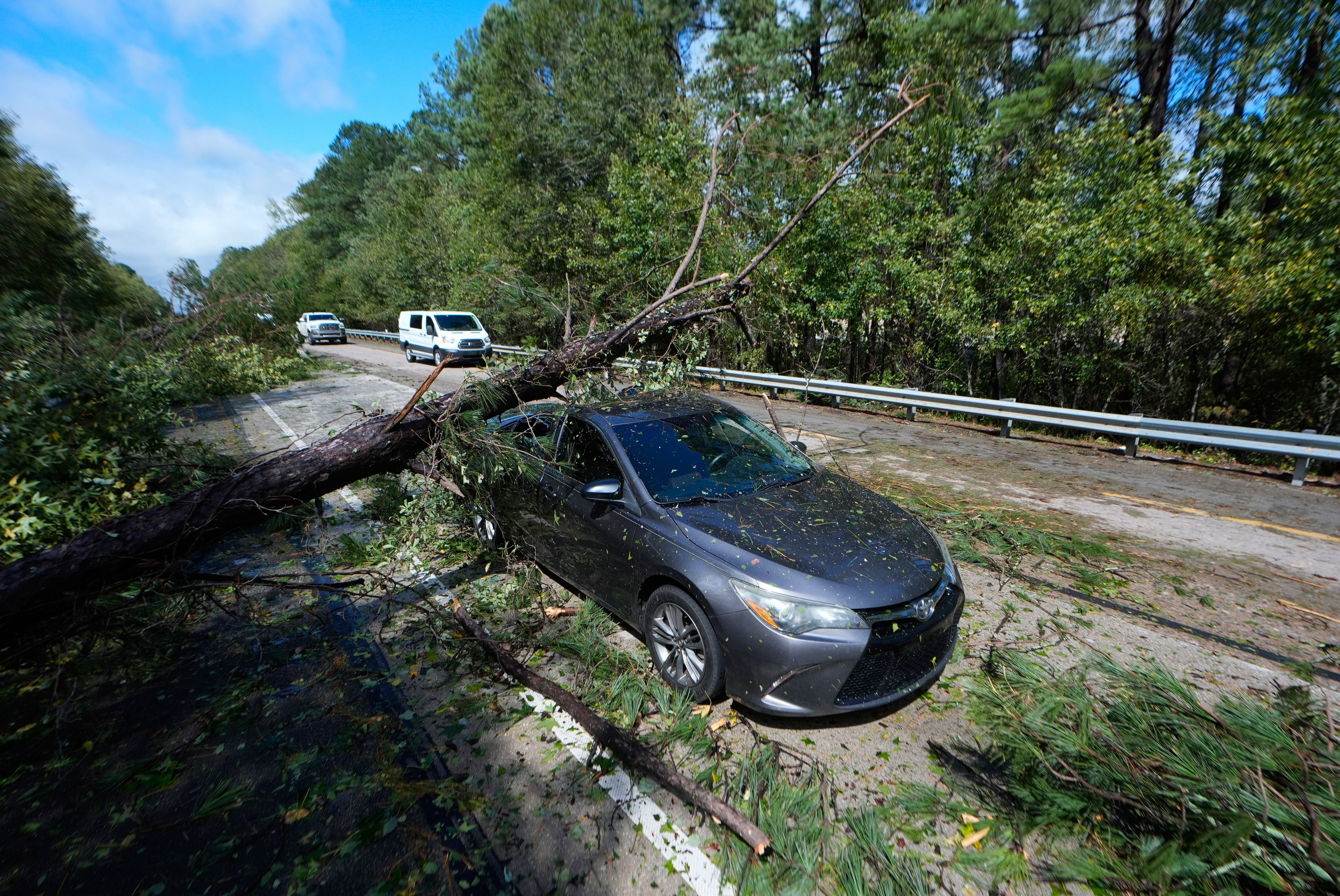 A tree rests on an adandoned car on Interstate 20 in the aftermath of Hurrican Helene Friday, Sept. 27, 2024, Grovetown, Ga. (AP Photo/John Bazemore)