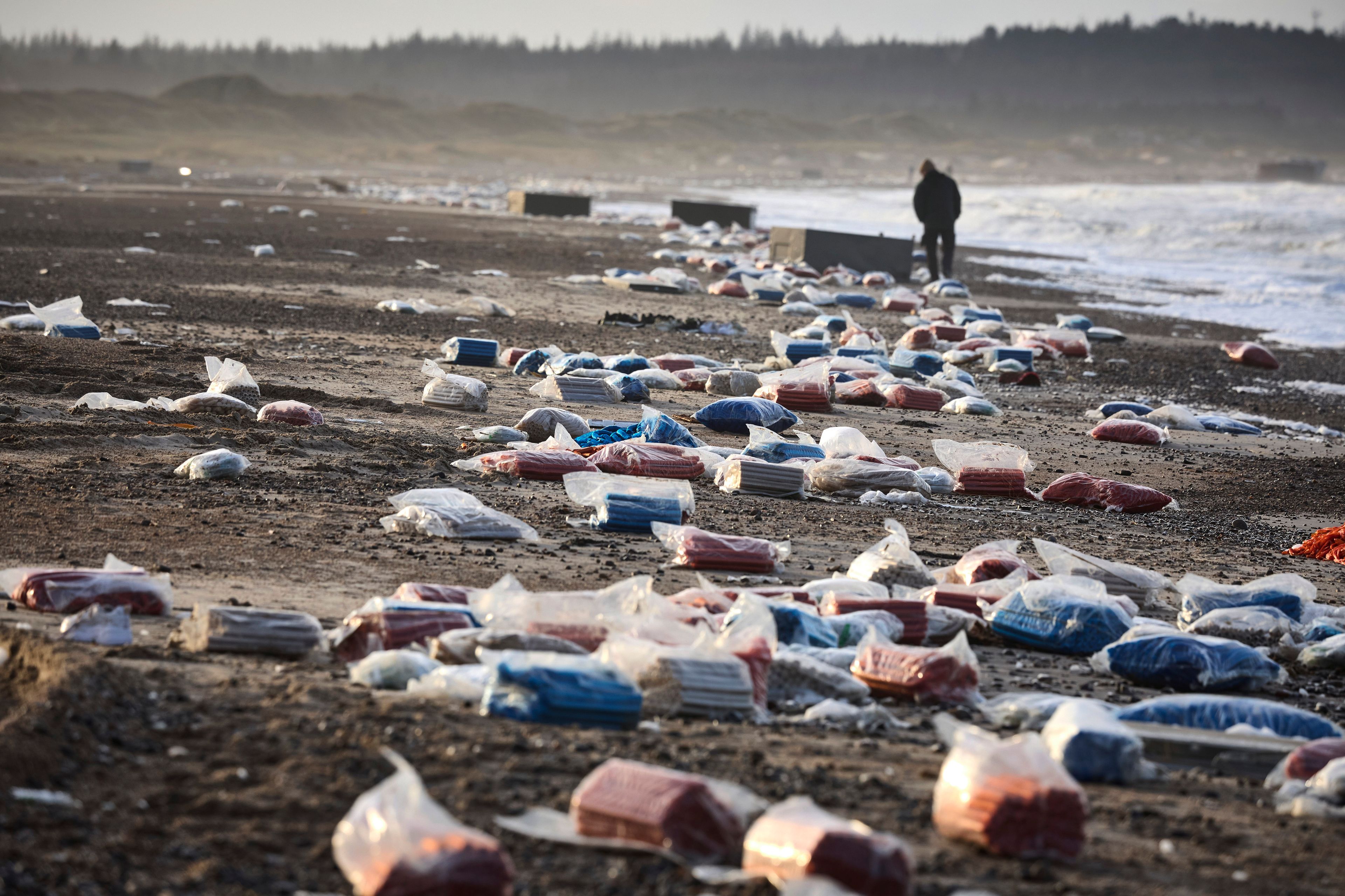 FILE - A person walks past detritus in the area between Tranum and Slette beach in Denmark, Saturday, Dec. 23, 2023, a day after a Maersk ship dropped 46 containers off the coast between Bulbjerg and Svinkloev in the northwestern part of Jutland, during storm Pia. (Claus Bjoern Larsen/Ritzau Scanpix via AP, File)