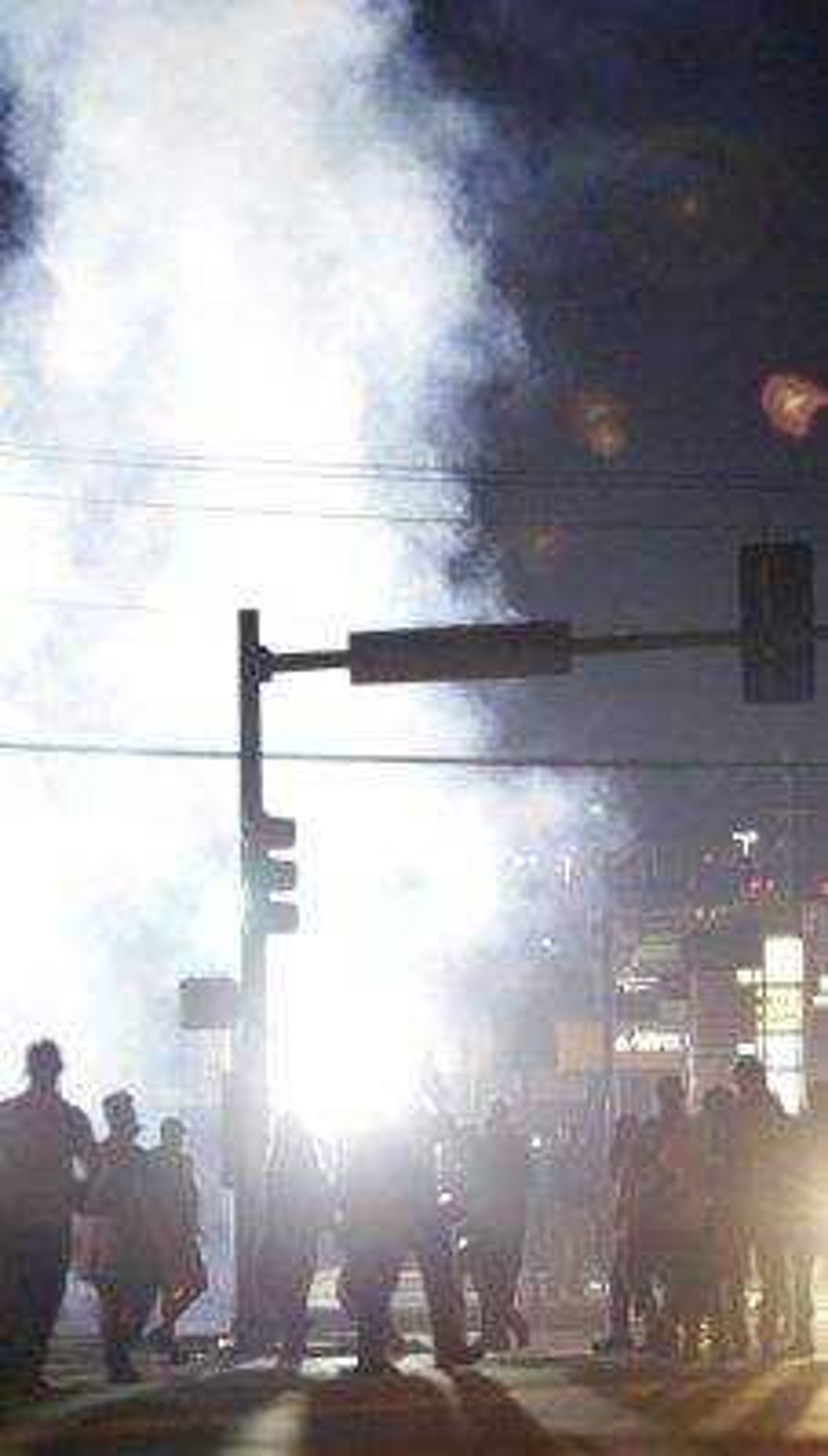 People stand near a cloud of tear gas Aug. 18 in Ferguson, Missouri, during protests over the Aug. 9 shooting of unarmed black 18-year-old Michael Brown by a white police officer. The U.S. government agreed to a police request to shut down several miles of airspace surrounding Ferguson, even though authorities said their purpose was to keep media helicopters away during protests in August, according to recordings of air traffic control conversations obtained by The Associated Press.