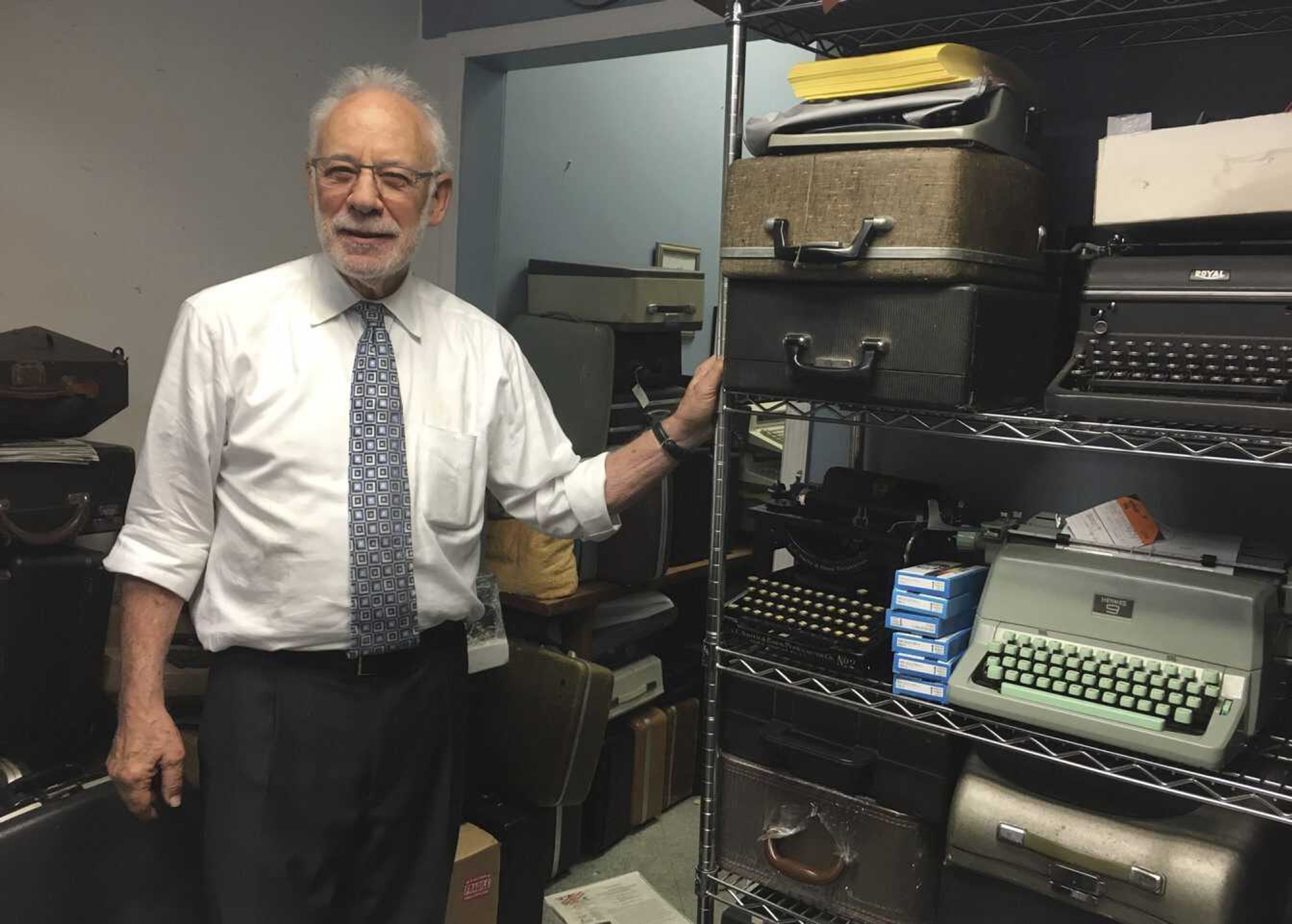 Paul Schweitzer poses for a photo June 28 in the Gramercy Typewriter Co. repair shop in New York, alongside a shelf of vintage typewriters. Schweitzer who, with his son, owns the Gramercy Typewriter Co., founded by Schweitzer's father in 1932. Vintage typewriters are sent for repair and restoration daily from around the country, Schweitzer said.