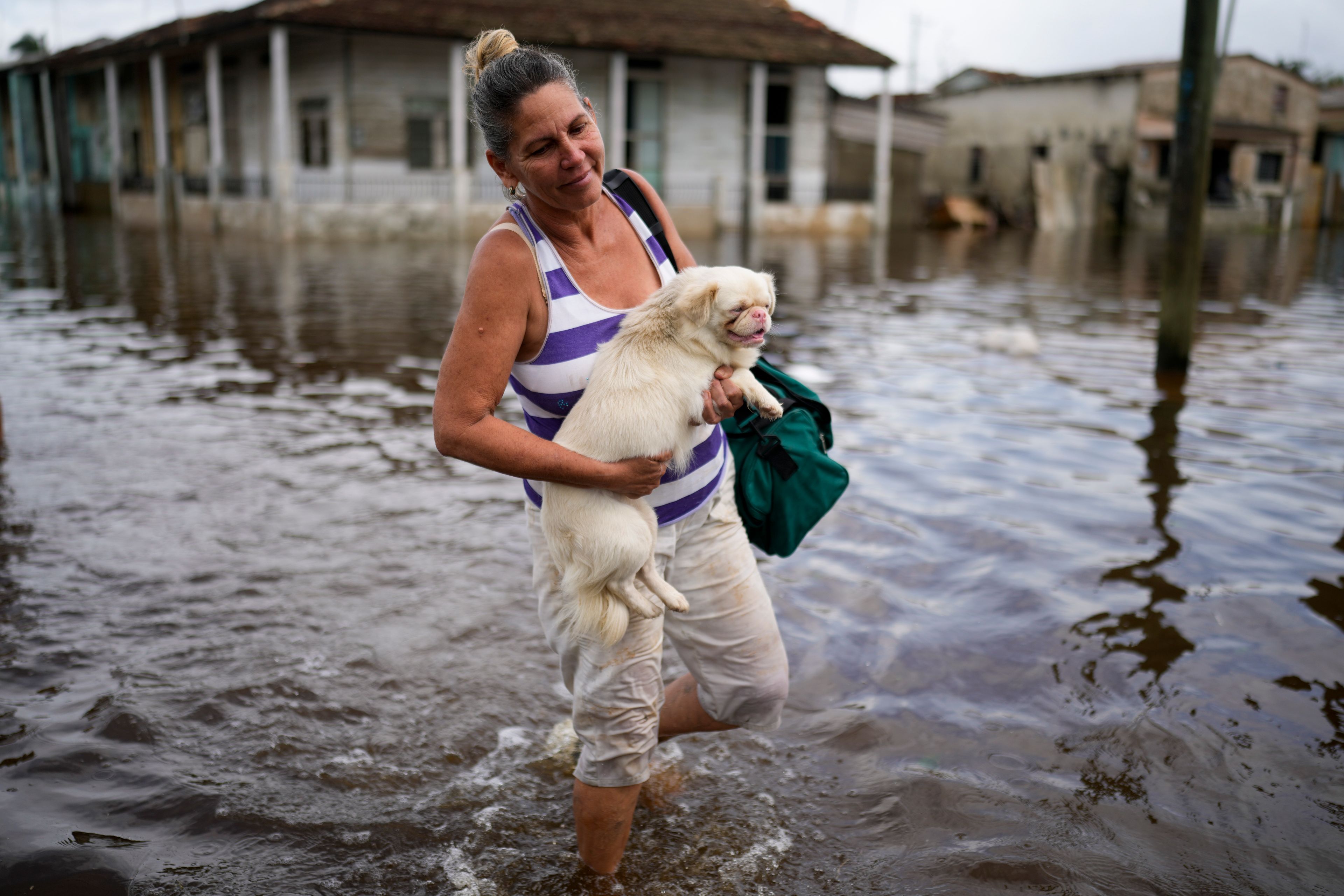 Madeleine Mur carries her dog through a flooded street after Hurricane Rafael passed through Batabano, Cuba, Thursday, Nov. 7, 2024. (AP Photo/Ramon Espinosa)