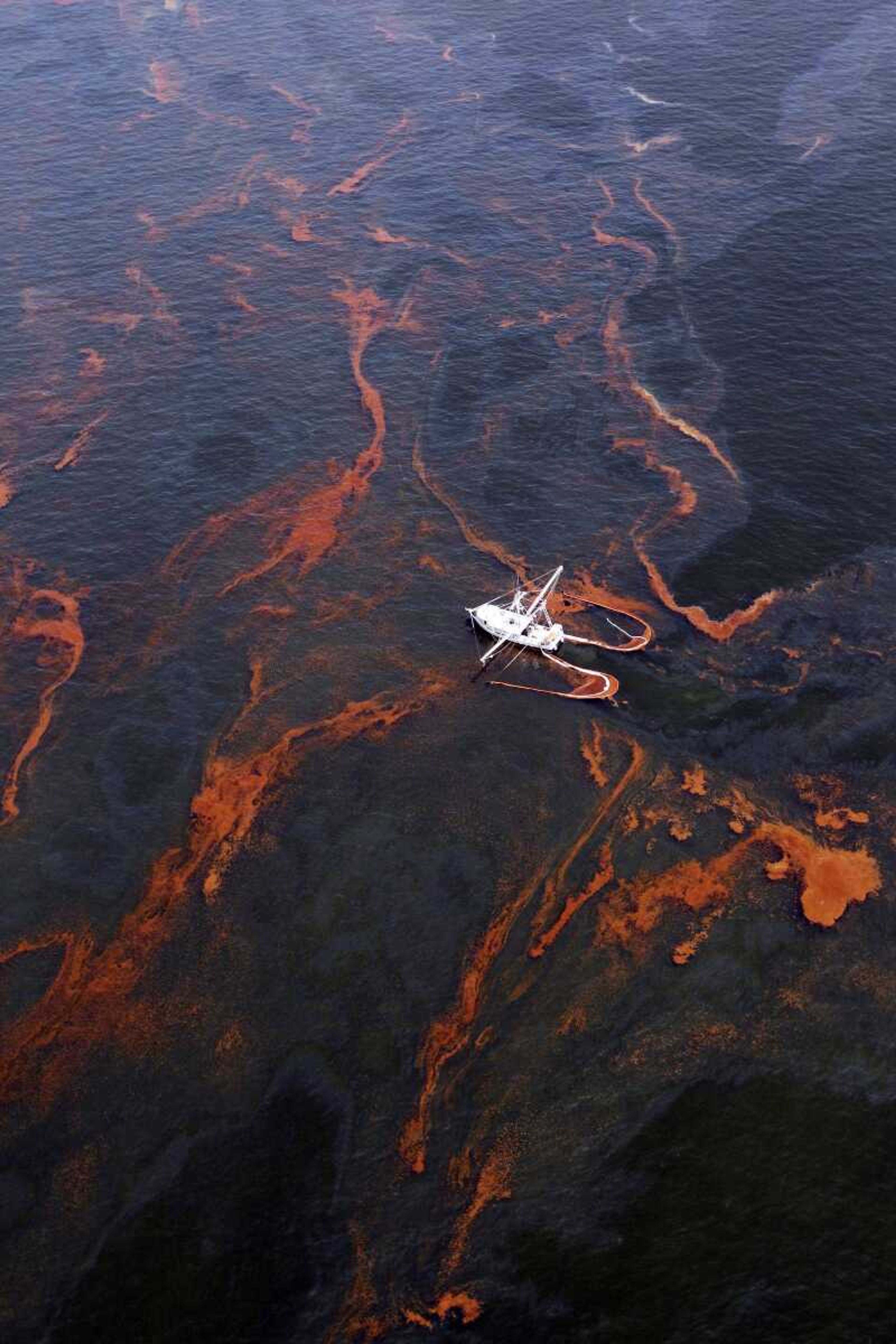 FILE -In this Wednesday, May 5, 2010 file photo, A shrimp boat is used to collect oil with booms in the waters of Chandeleur Sound, La. The U.S. Justice Department and the five Gulf coast states most affected by a massive 2010 oil spill have all indicated they would like to reach a settlement on civil claims against BP PLC that would avoid a trial scheduled to start next week. (AP Photo/Eric Gay)