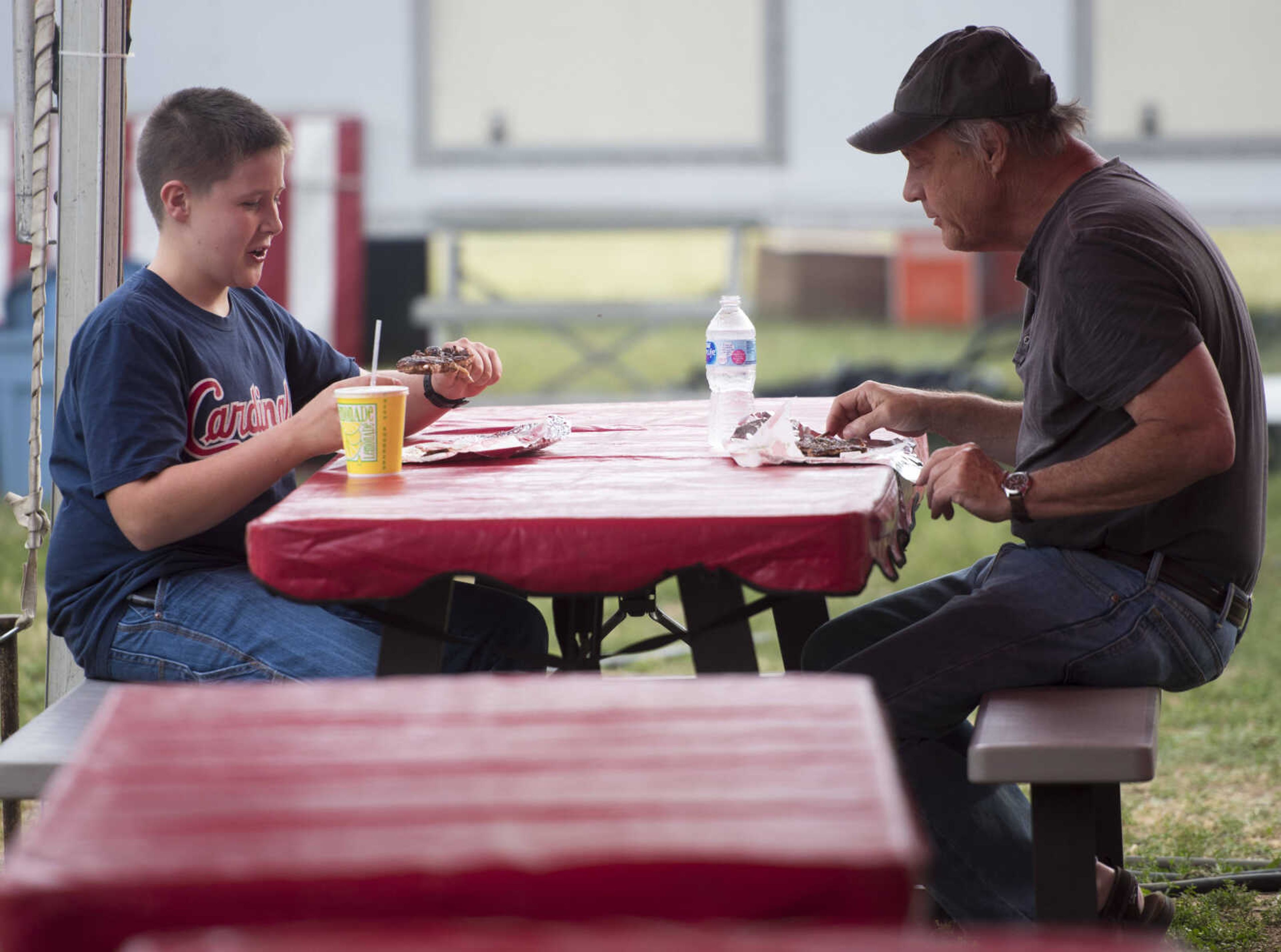 Joey Hazard, 13, eats pork steak on a stick with his grandfather, Tim Pekios, at the SEMO District Fair on September 11, 2017, in Cape Girardeau.